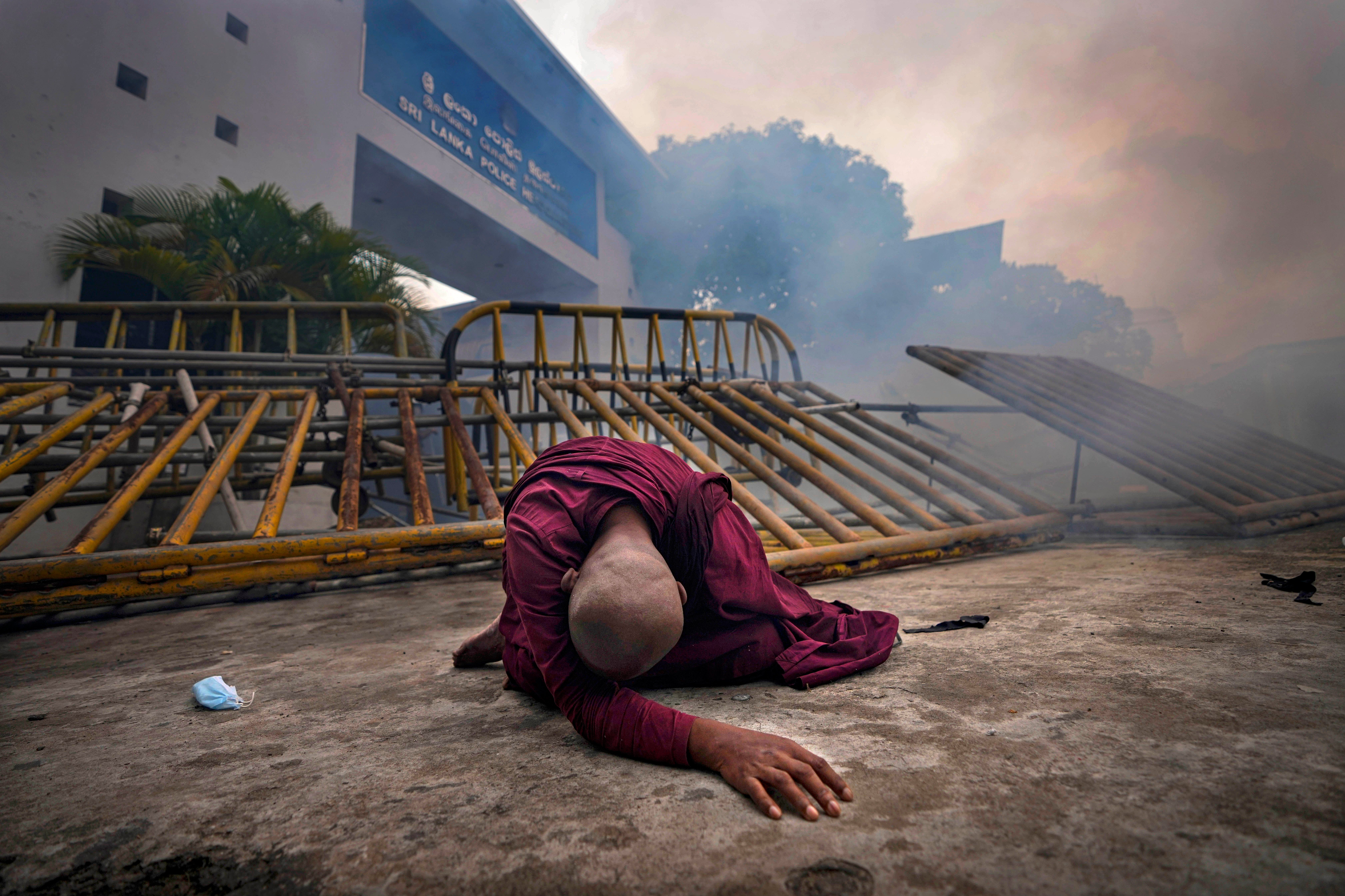 A Buddhist nun falls next to a barricade after inhaling tear gas during a protest against the economic crisis, outside police headquarters in Colombo, on 9 June