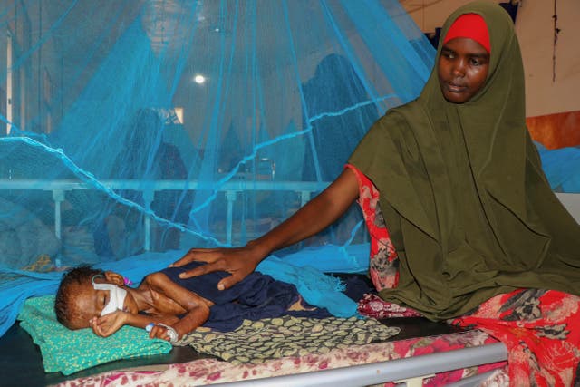 <p>Dhahira Hassan Ali sits with her one-year-old son Adan as he is fed via a nasogastric feeding tube to treat his severe acute malnutrition, at the stabilization center of Bay Regional Hospital in Baidoa, Somalia</p>