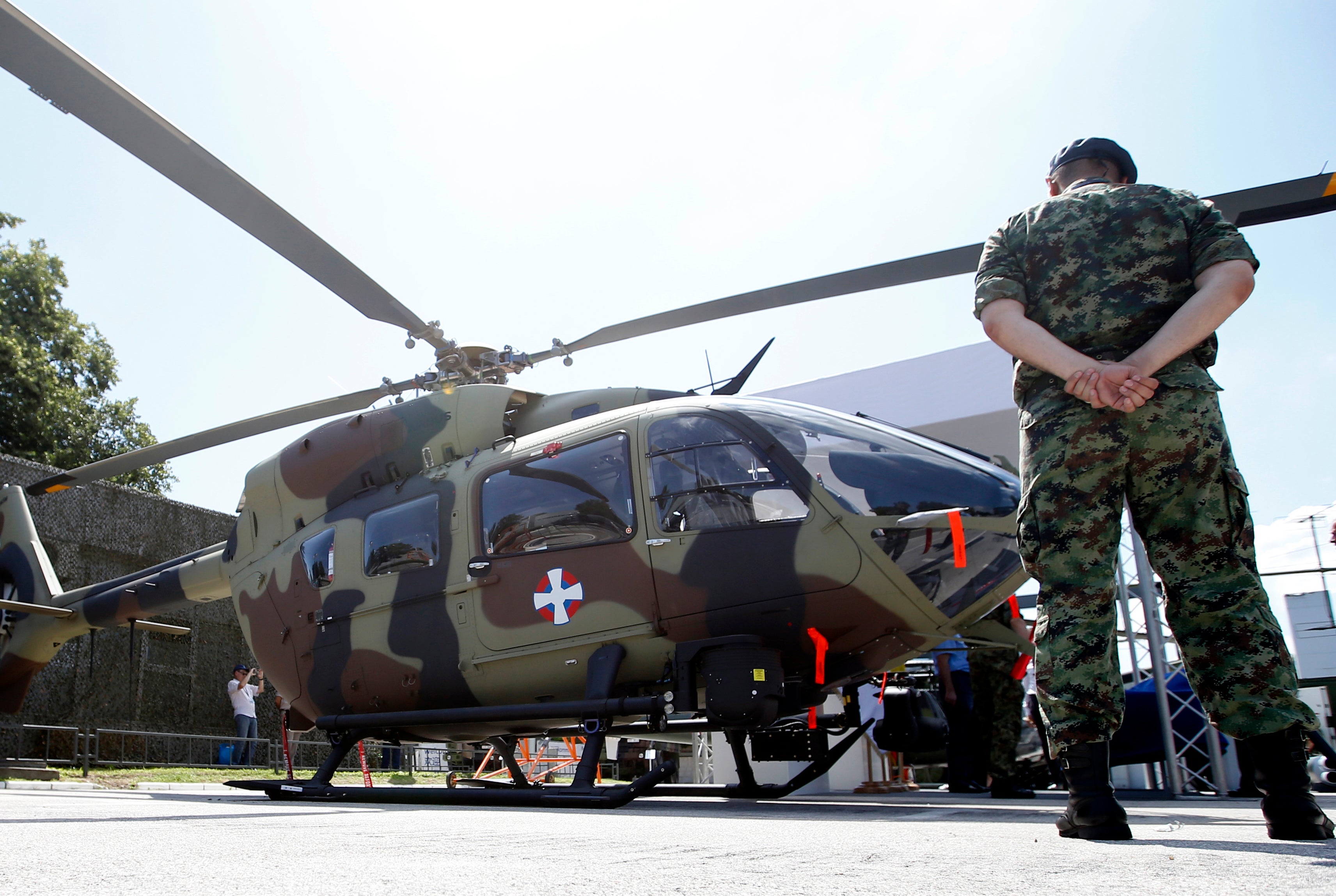 A Serbian army officer stands by an Airbus H145M multi-utility helicopter during an arms fair in Belgrade