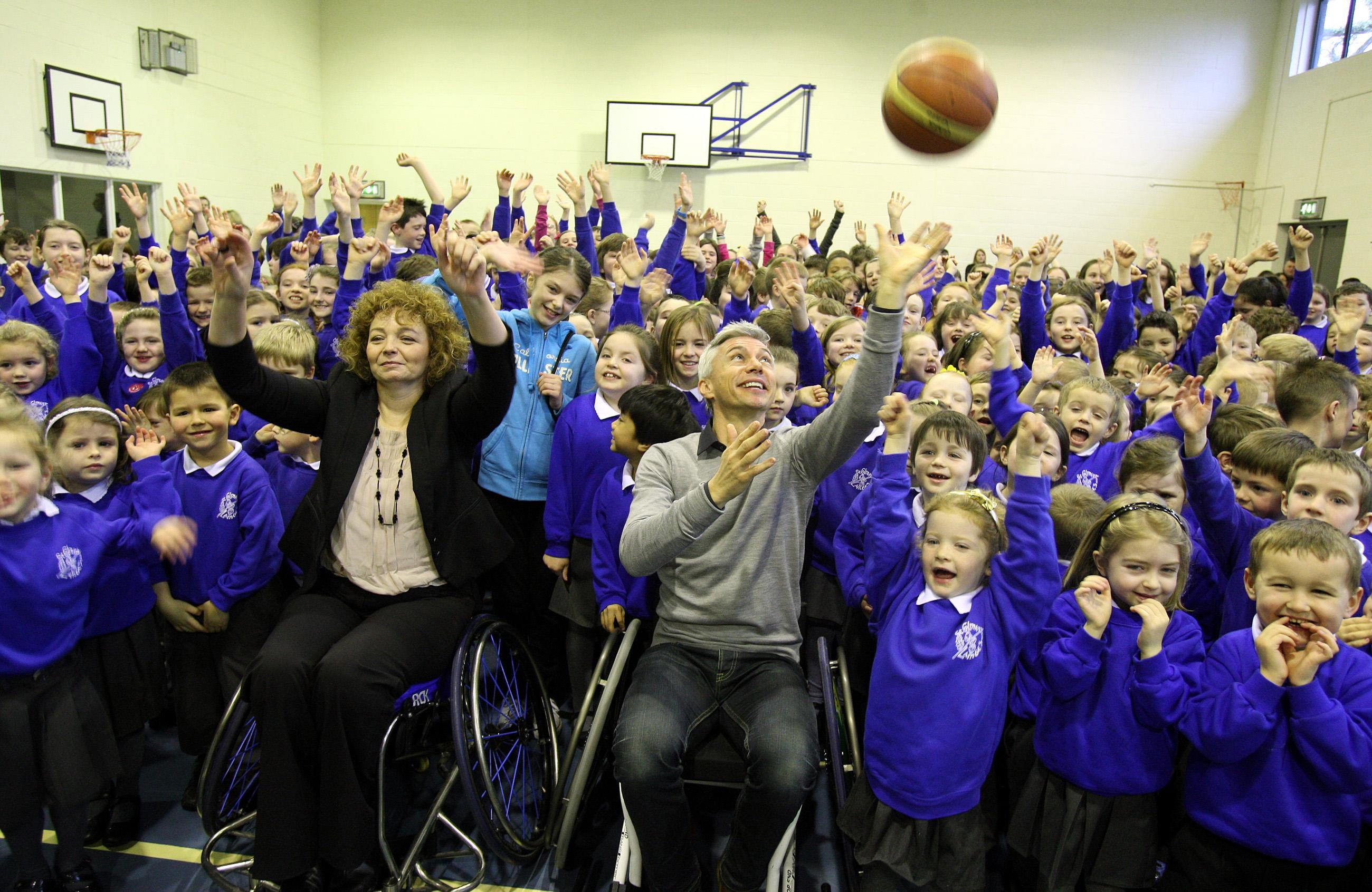 Olympic gold medallist Jonathan Edwards (centre) demonstrates wheelchair basketball to pupils at St Colmans Primary School, Belfast