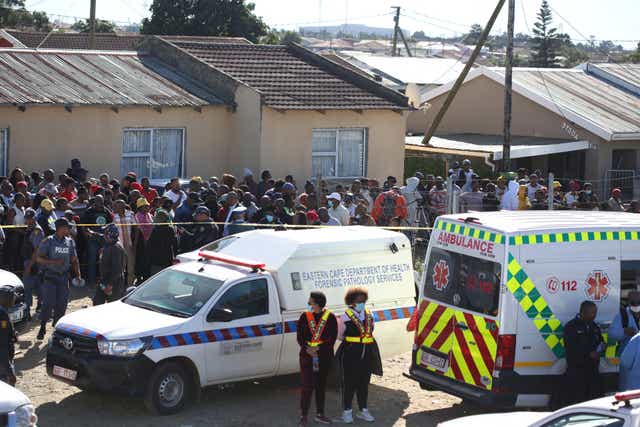 <p>A crowd gathers as forensic personnel investigate after the deaths of patrons of the Enyobeni Tavern</p>