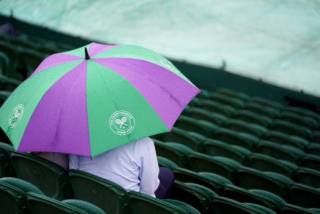 Spectators shelter from the rain on day one of Wimbledon (Zac Goodwin/PA)