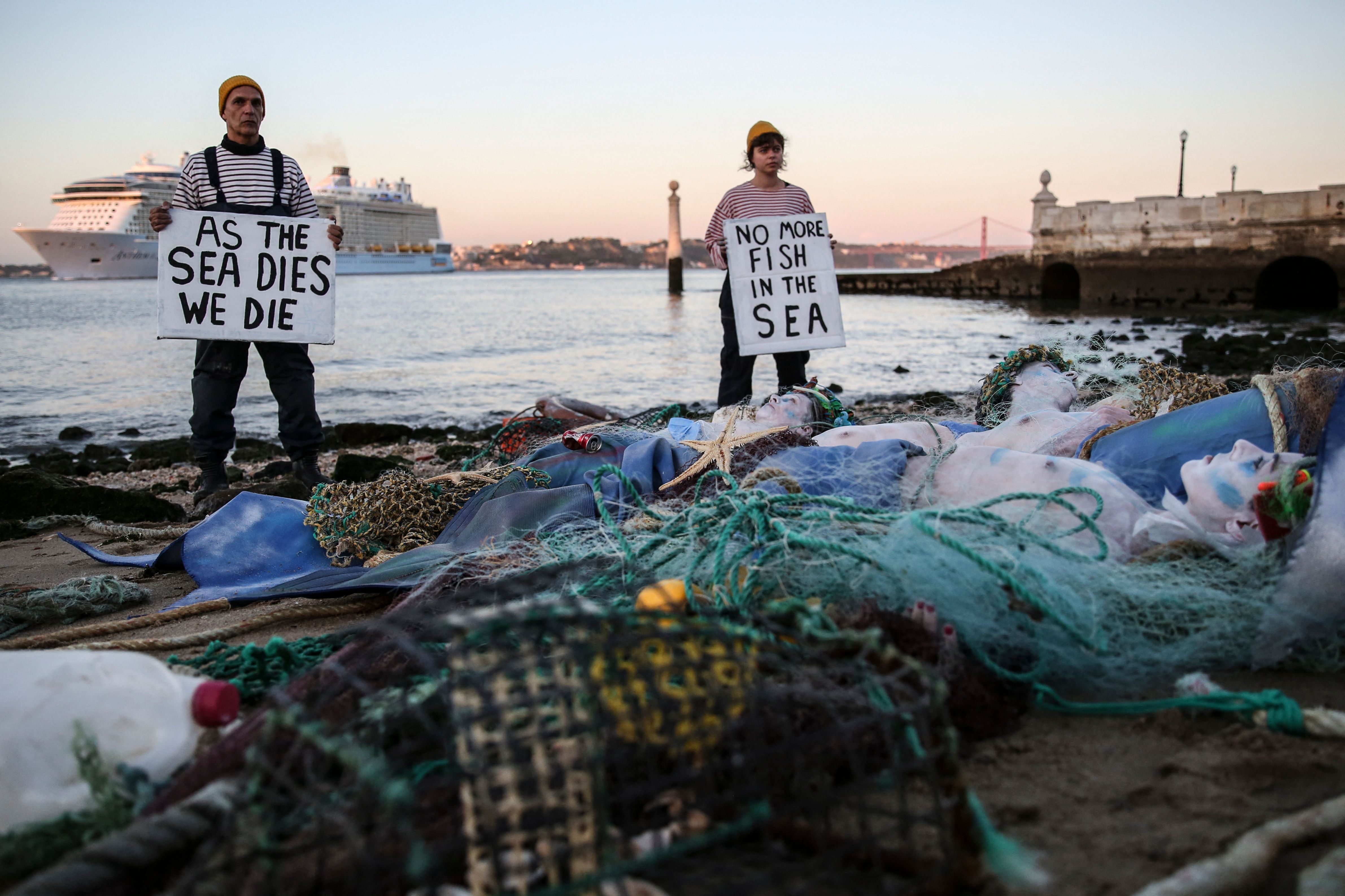 Ocean Rebellion activists hold banners reading “As the sea dies we die” and “No more fish in the sea” as they stage a protest in Terreiro do Paco, Lisbon on June 27, 2022, before the UN Ocean Conference