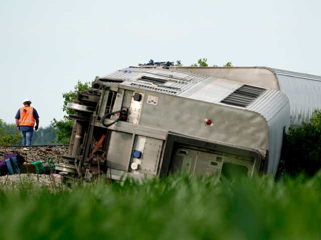 <p>A worker inspects a derailed Amtrak train near Mendon, Missouri, on Monday 27 June 2022</p>