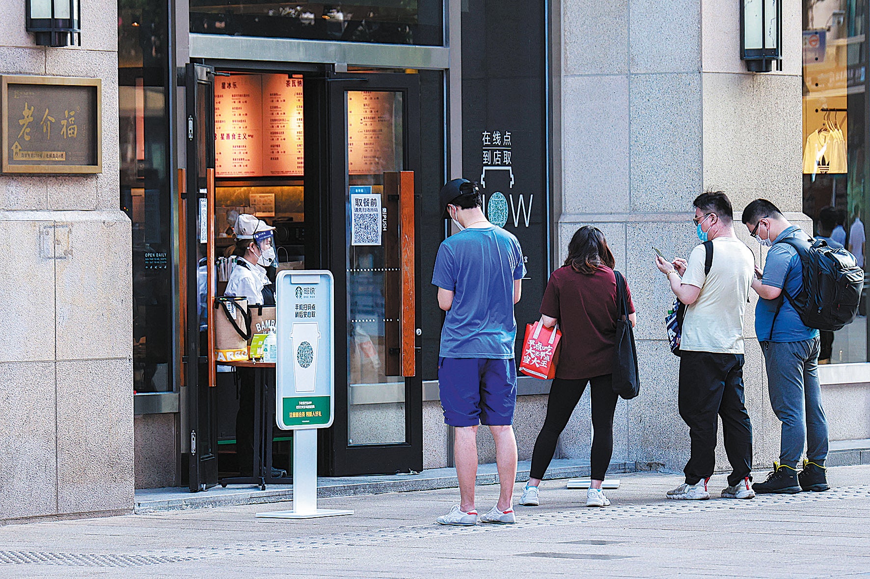 Customers use their phones to buy coffee outside a Starbucks branch in Shanghai on June 2
