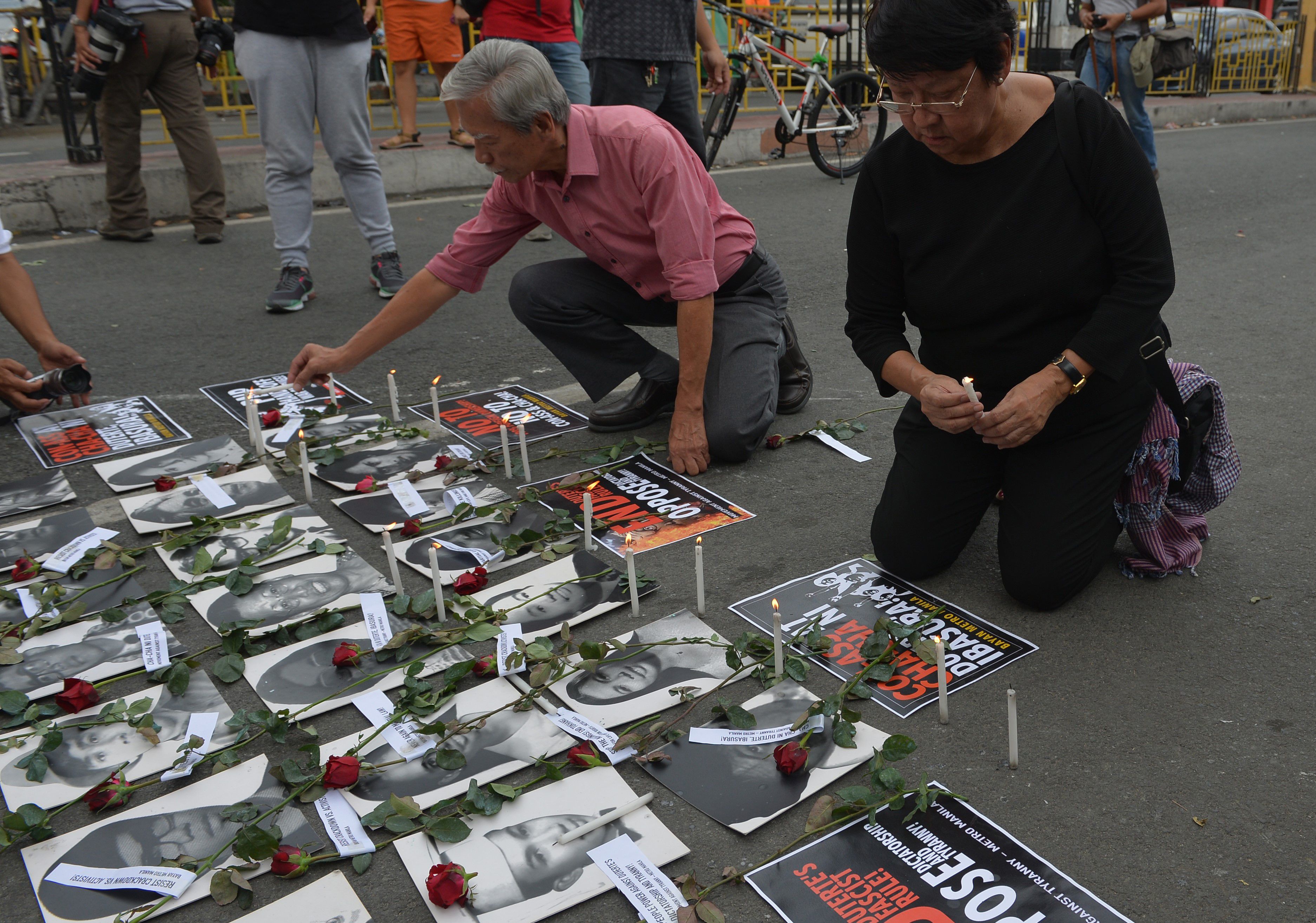 Judy Taguiwalo (right) placing candles on photos of some of the activists who were victims during martial law under the dictator Ferdinand Marcos