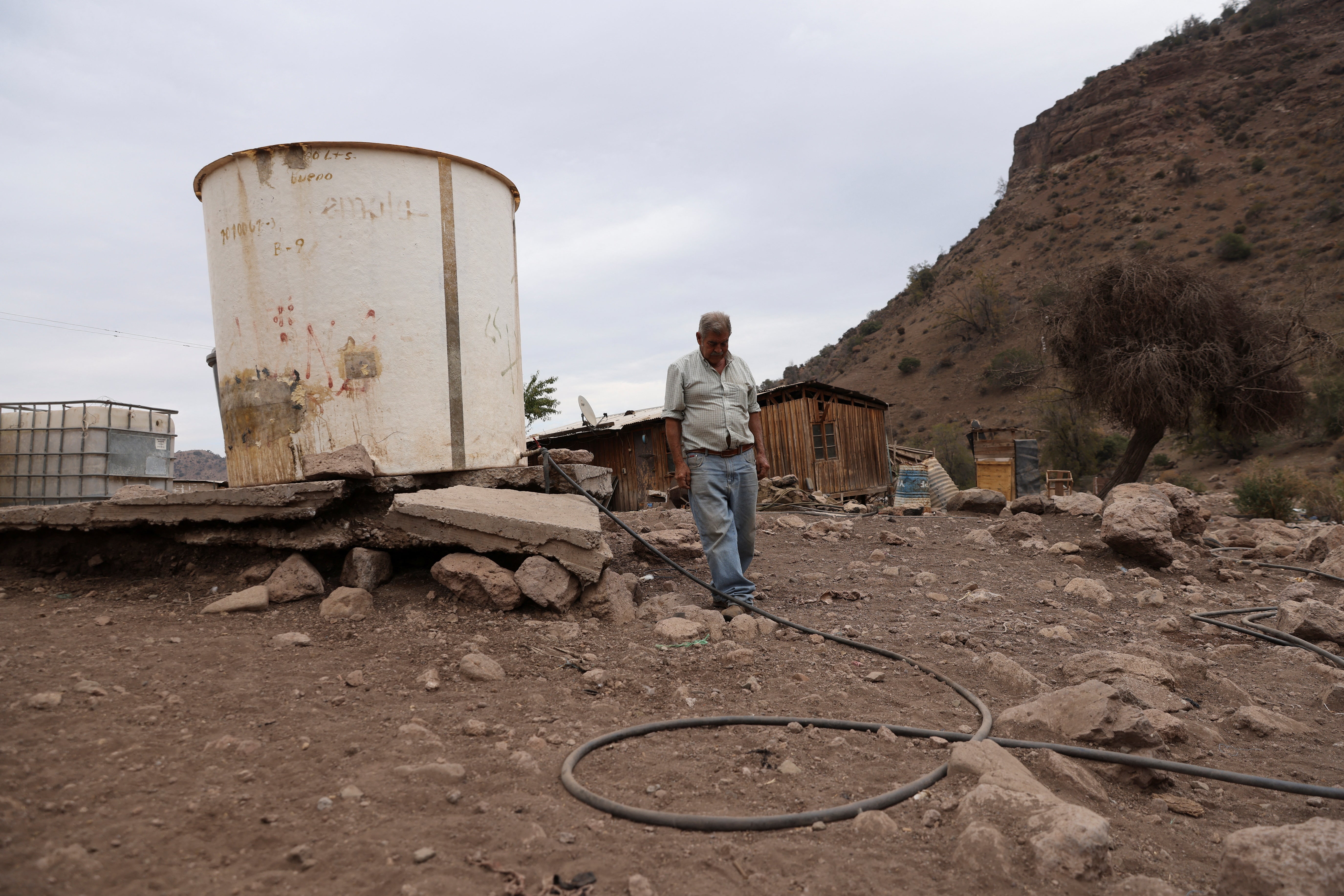 Segundo Aballay, a rancher, walks next to a water container used for his animals