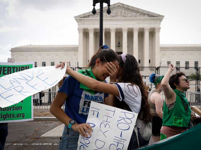<p>Abortion rights activists Carrie McDonald  (L) and Soraya Bata react to the Dobbs v Jackson Women's Health Organization ruling which overturns the landmark abortion Roe v. Wade case in front of the U.S. Supreme Court on June 24, 2022 in Washington, DC</p>