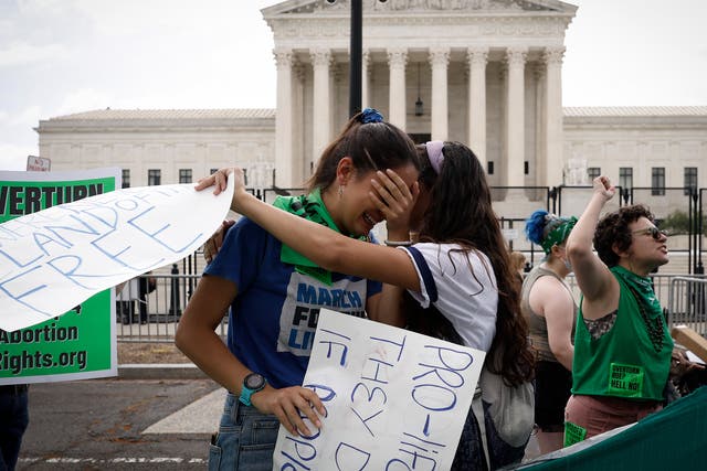 <p>Abortion rights activists Carrie McDonald  (L) and Soraya Bata react to the Dobbs v Jackson Women's Health Organization ruling which overturns the landmark abortion Roe v. Wade case in front of the U.S. Supreme Court on June 24, 2022 in Washington, DC</p>