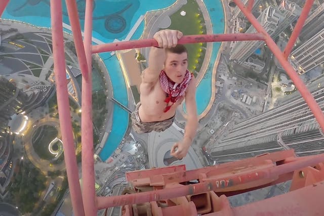 <p>Adam Lockwood hangs off a Dubai crane with one hand</p>