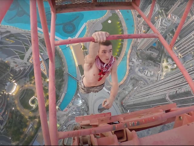 <p>Adam Lockwood hangs off a Dubai crane with one hand</p>