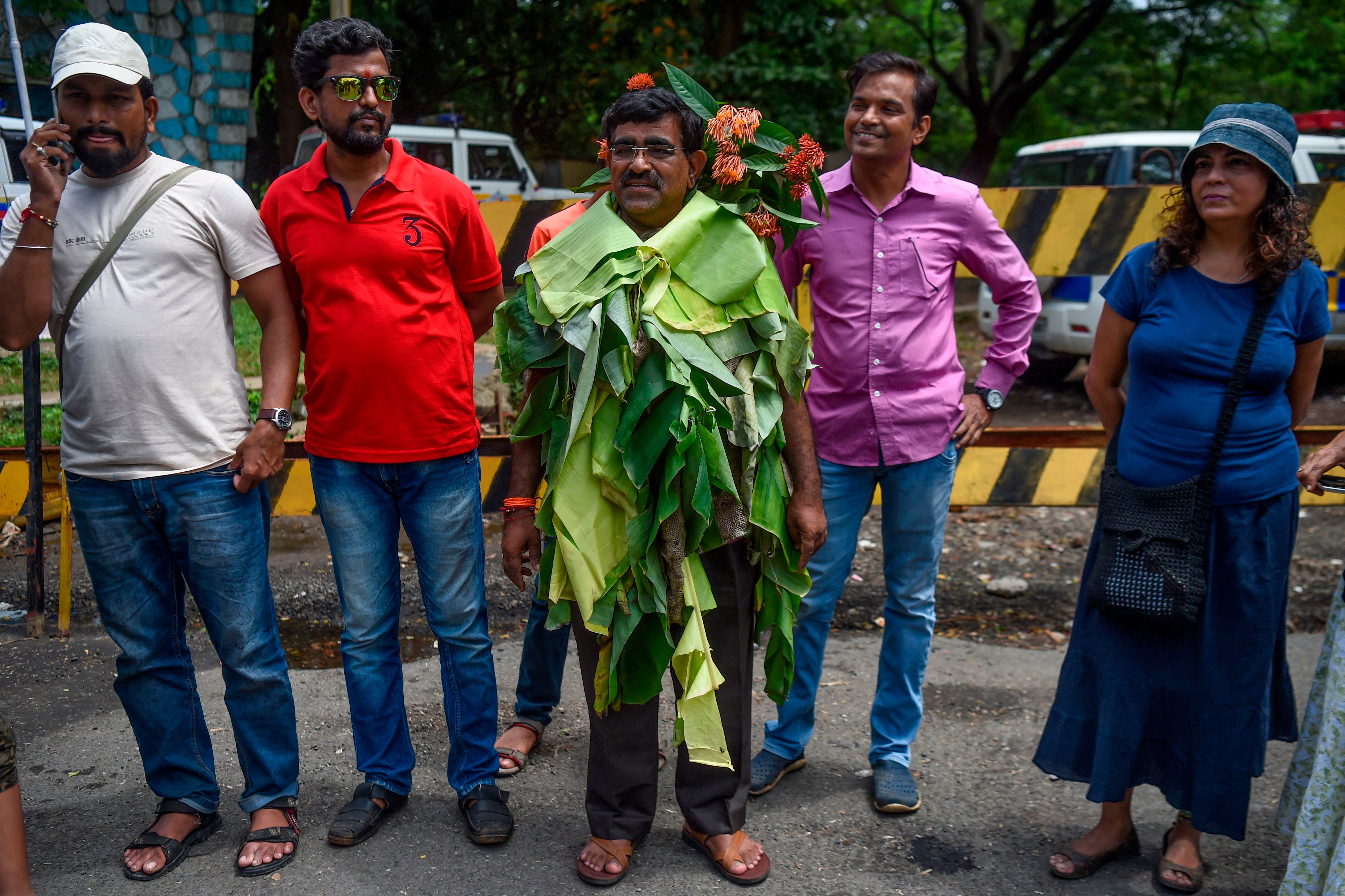 Activist Dadarao Bilhore (centre) stands wearing a dress made from banana leaves and flowers found in the Aarey forest as he protests against the destruction of Aarey forest