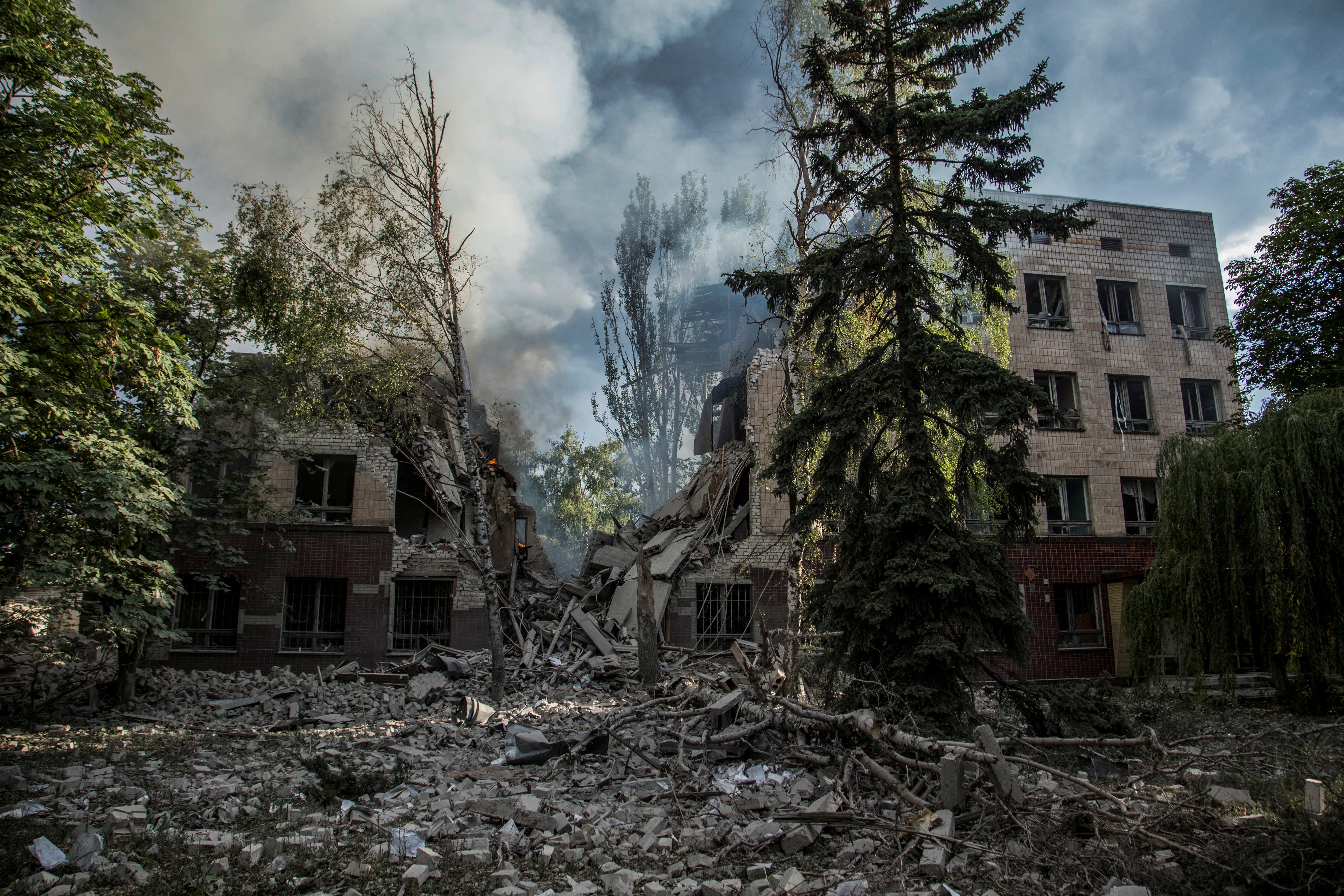 Smoke rises over the remains of a building destroyed by a military strike as Russia's attack on Ukraine continues