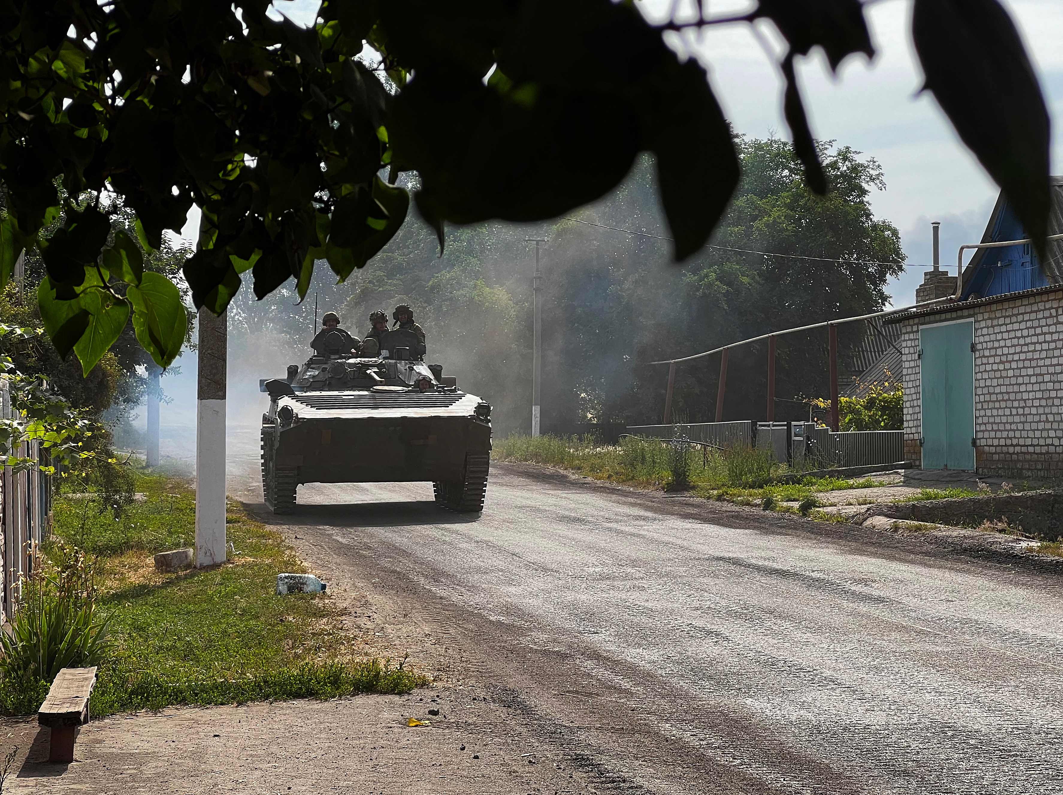 Ukrainian soldiers ride an armoured vehicle on the main road to Lysychansk