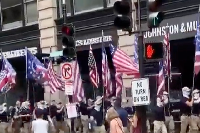 <p>A masked group of white supremacists marches through downtown Boston on 2 July, 2022.</p>