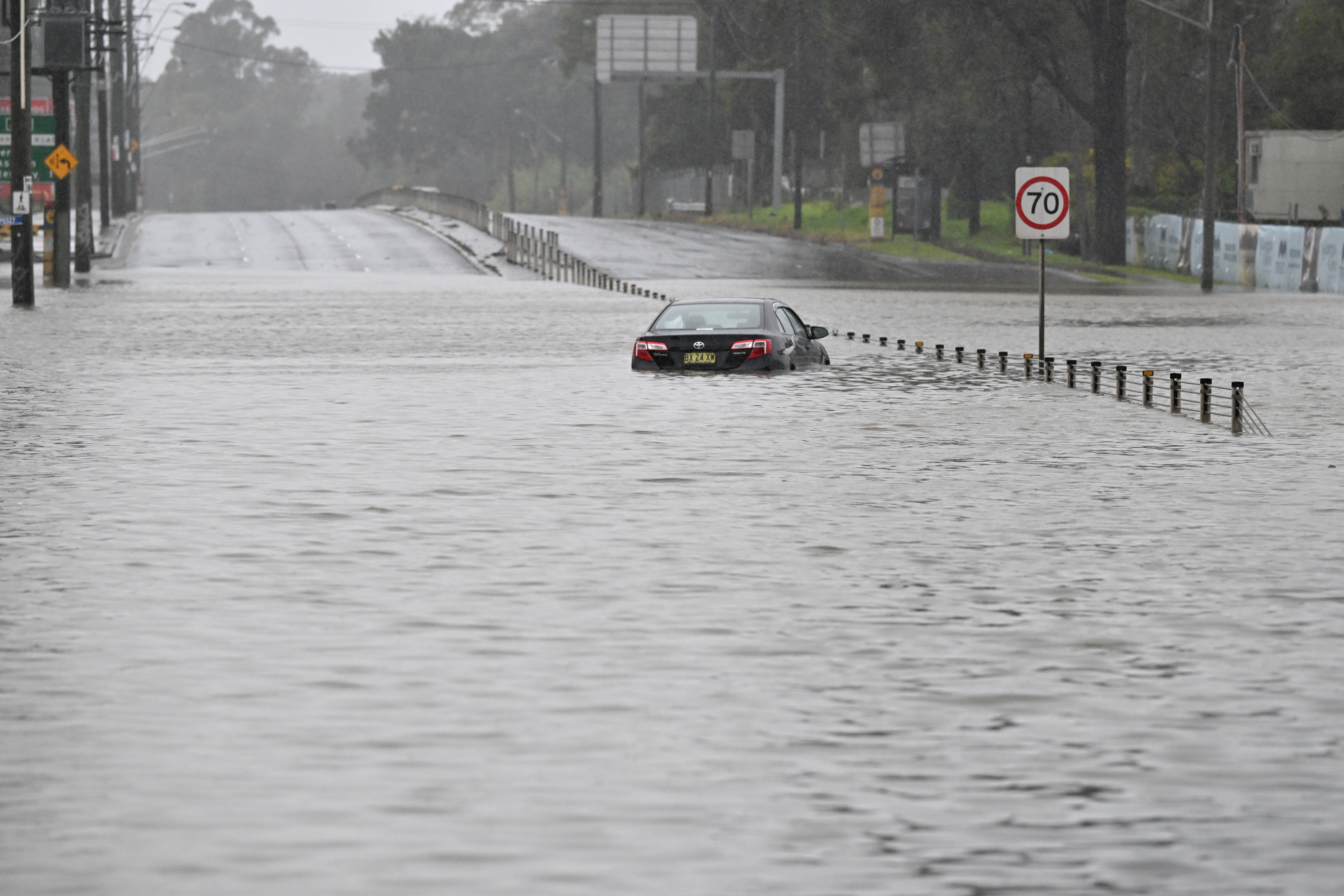 A car is seen abandoned in floodwaters on Newbridge Road in Chipping Norton in Western Sydney