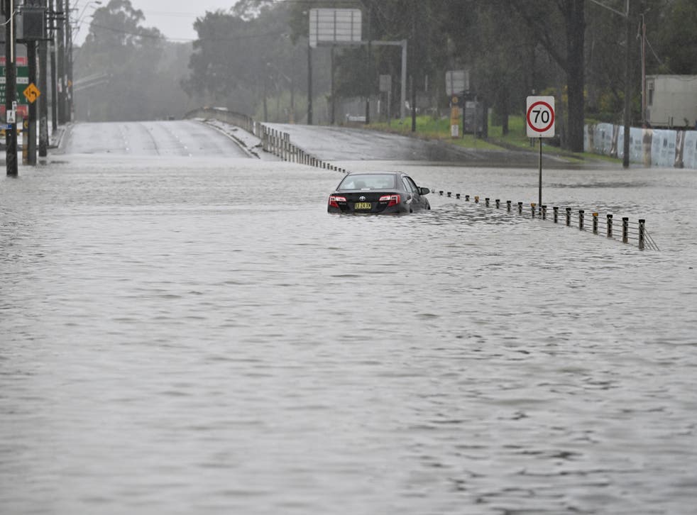 <p> A car is seen abandoned in floodwaters on Newbridge Road in Chipping Norton in Western Sydney</p>