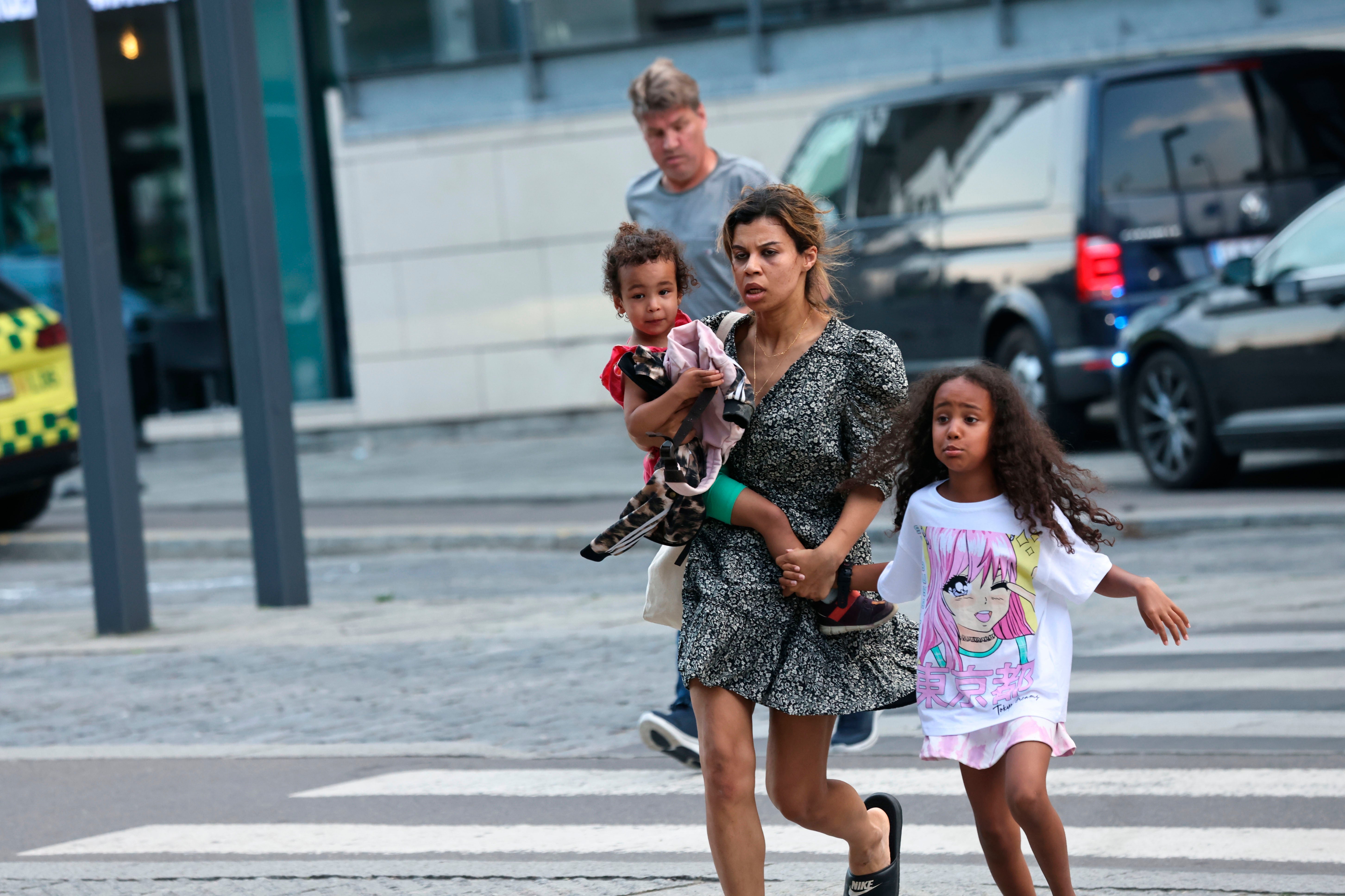 A woman and children flee the Field’s shopping centre (Olafur Steinar Gestsson/Ritzau Scanpix via AP)