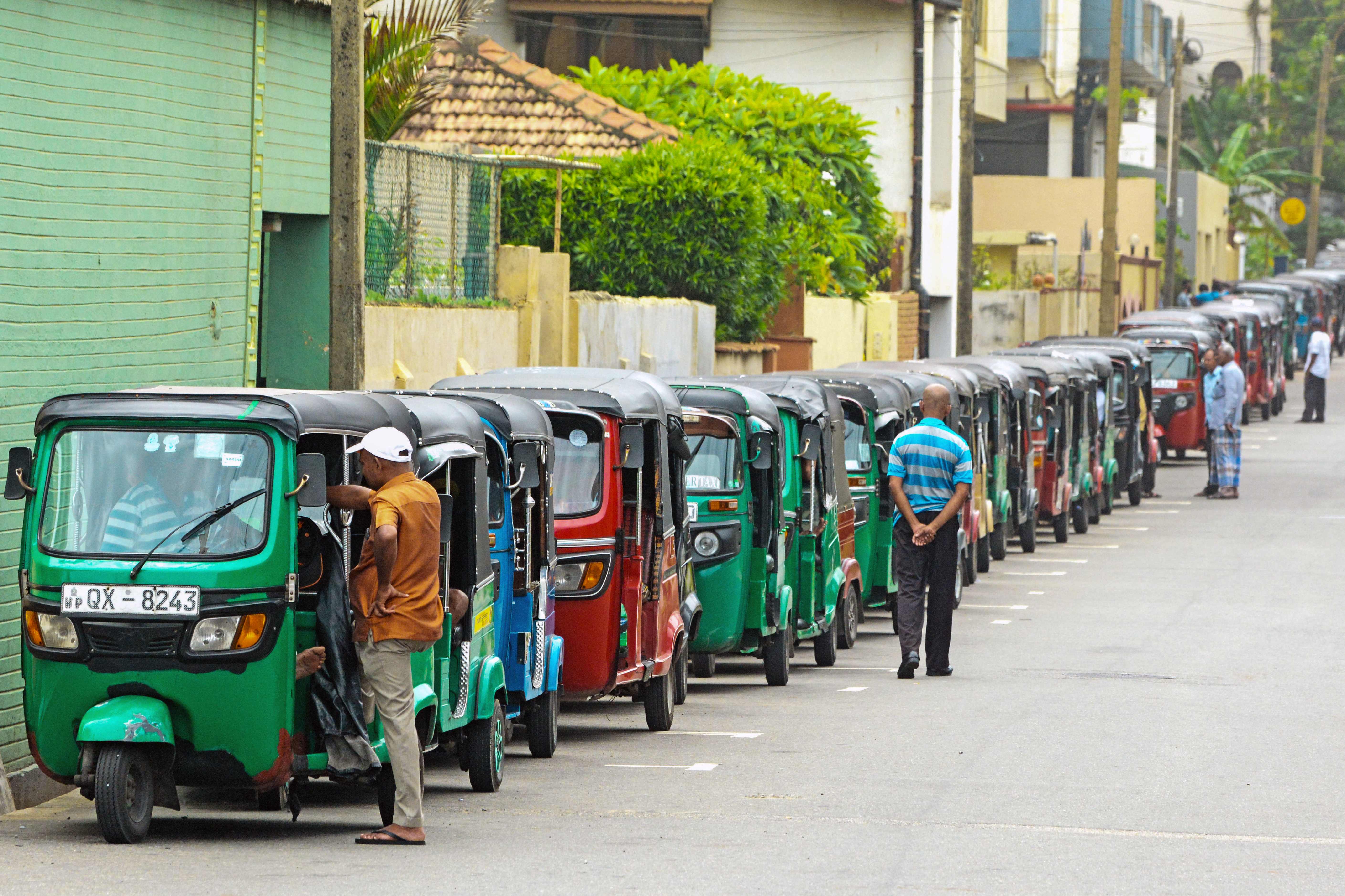 Auto rickshaw drivers queue along a street to buy fuel at a fuel station in Colombo, Sri Lanka