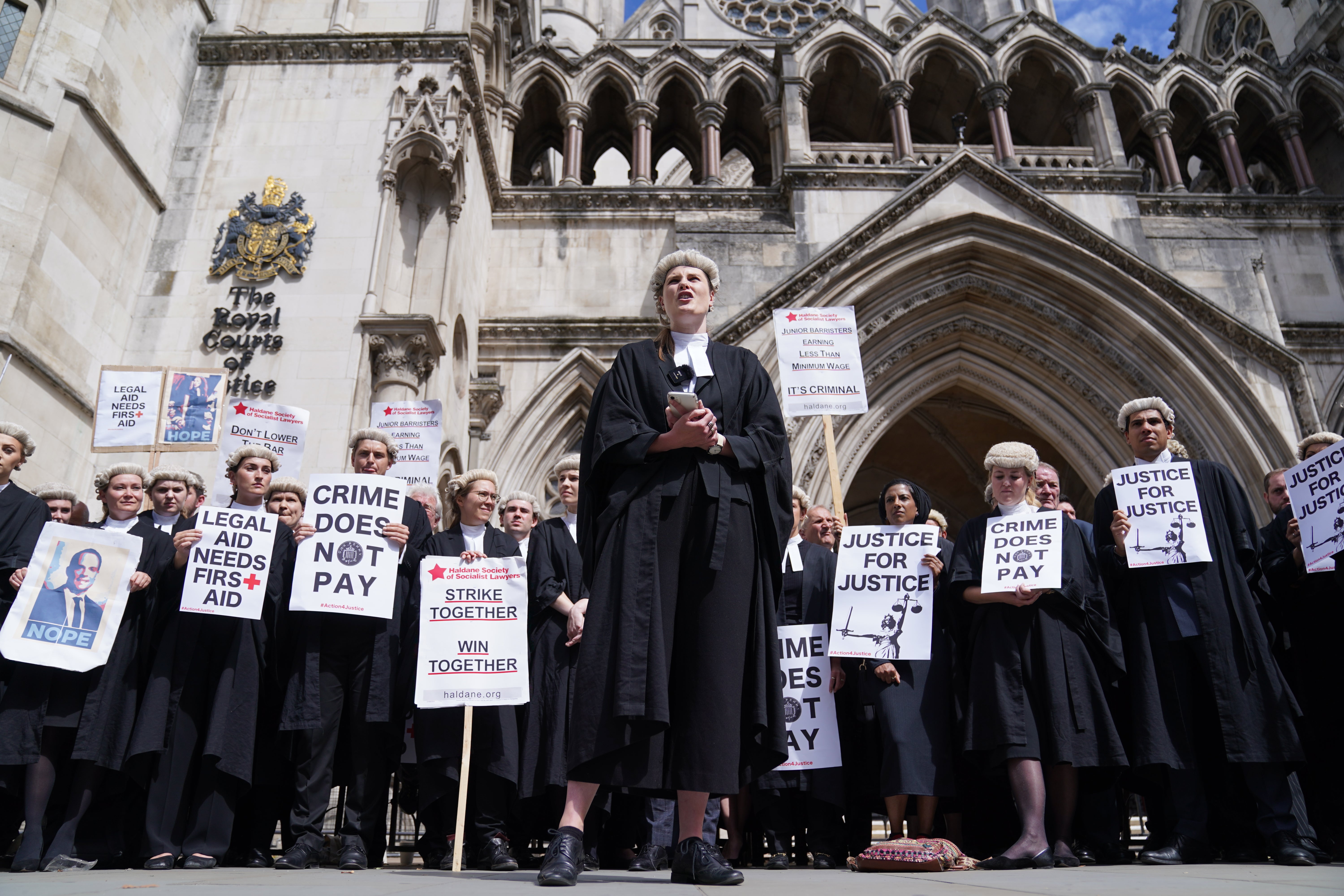 A junior barrister speaks to other criminal defence barristers as they gather outside the Royal Courts of Justice in London (Kirsty O’Connor/PA)