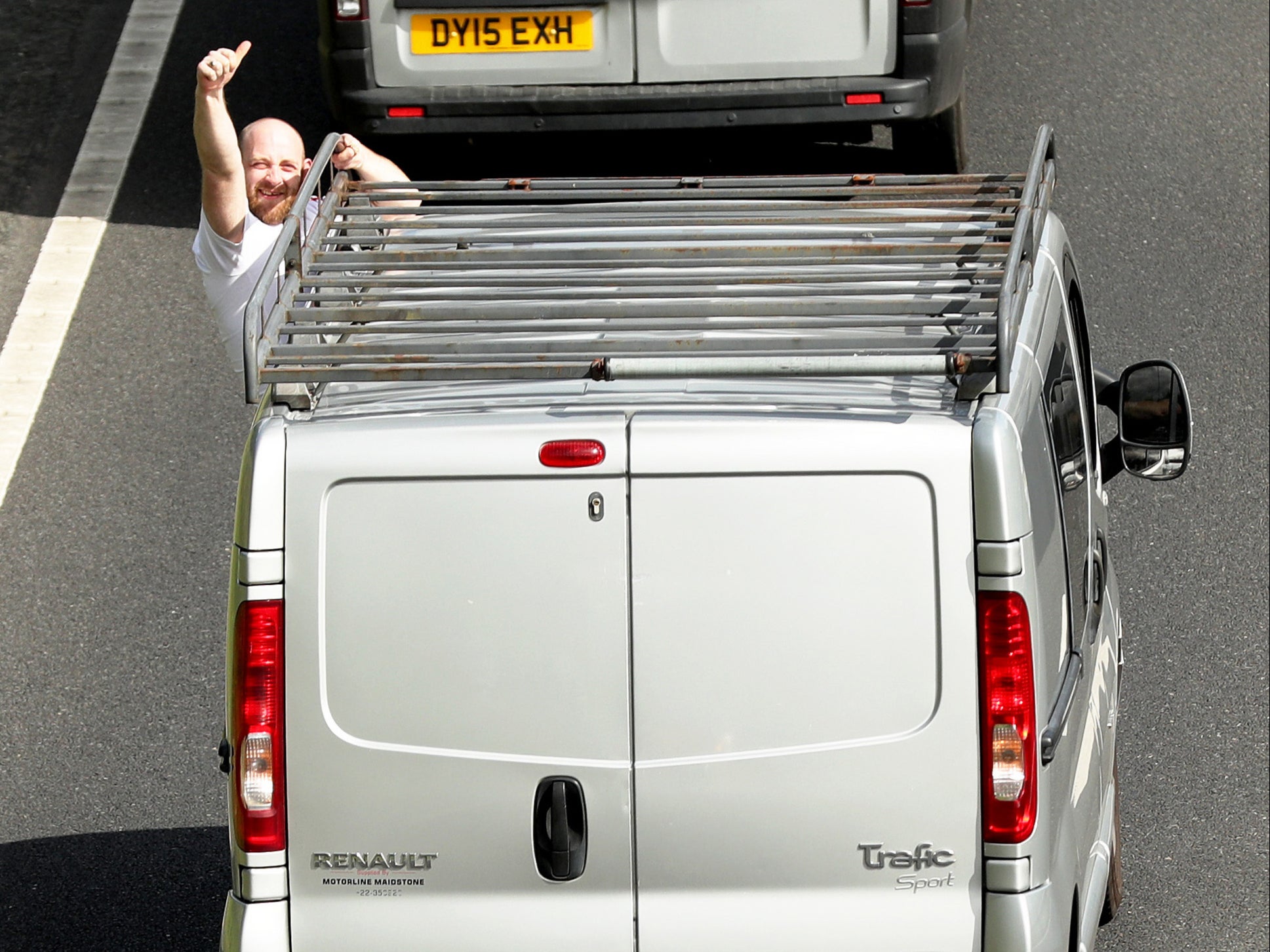 A protester gives a thumbs up as cars slow down traffic on the A64