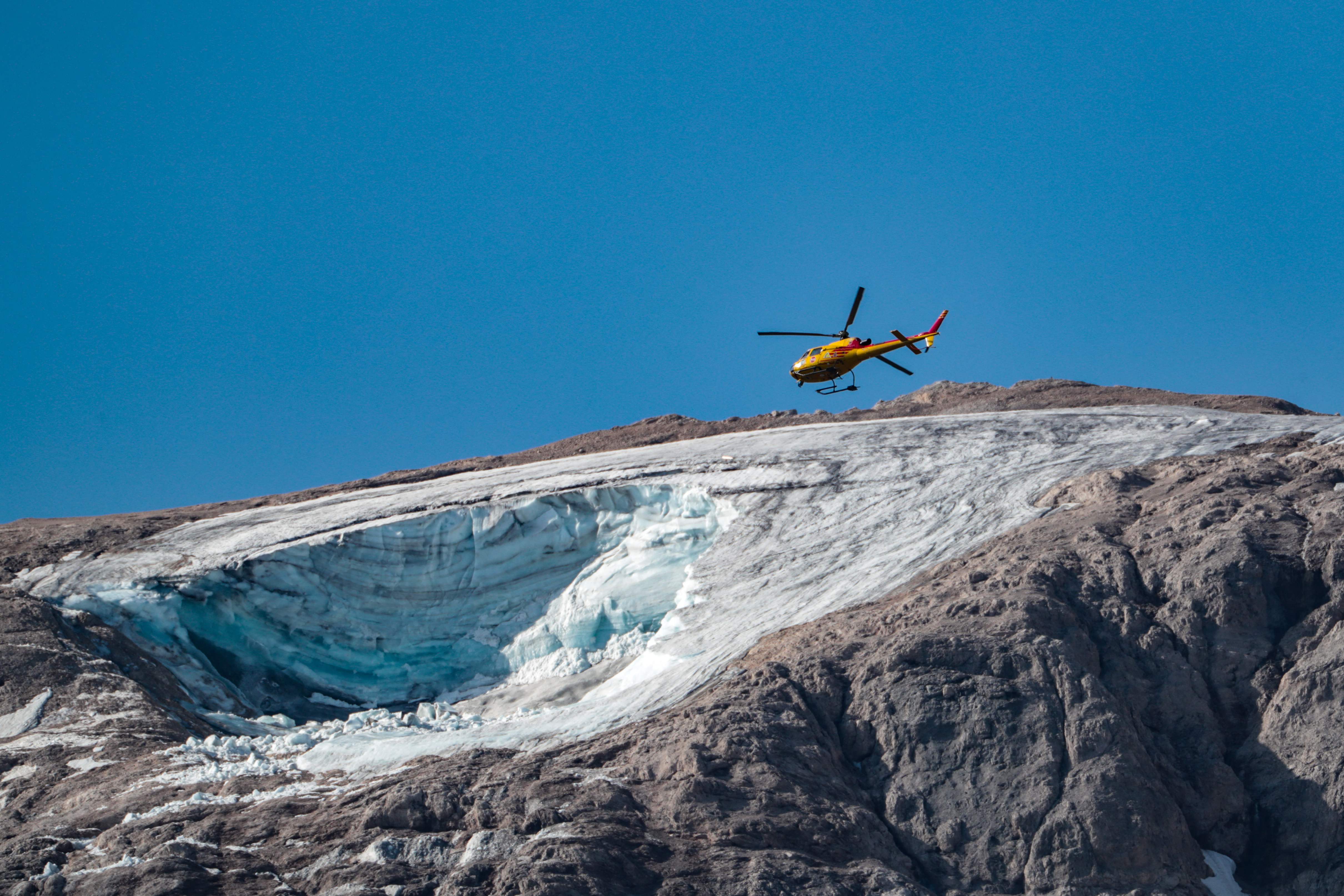 A rescue helicopter flies on July 4, 2022 over the glacier that collapsed the day before on the mountain of Marmolada, the highest in the Dolomites