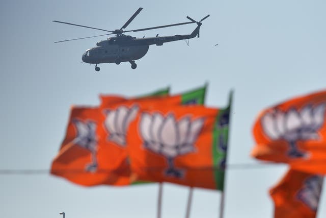 <p>An Indian Air Force helicopter carrying Indian prime minister Narendra Modi is seen over the flags of his Bharatiya Janata Party</p>