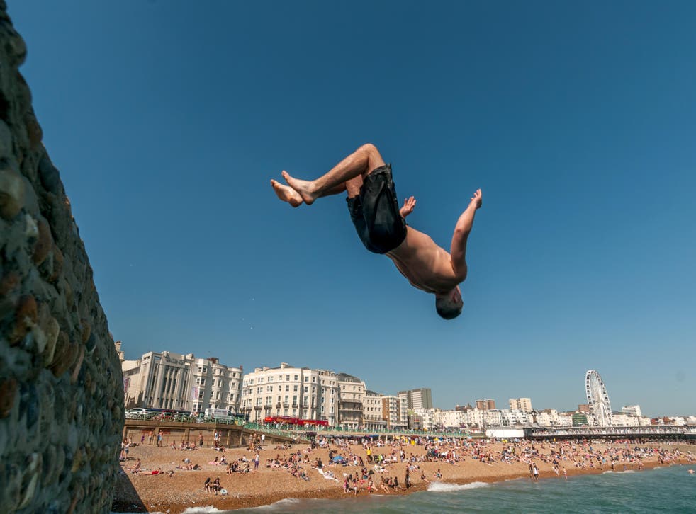 Young people jumping into the sea from the Banjo Groyne on Brighton beach (Alamy/PA)