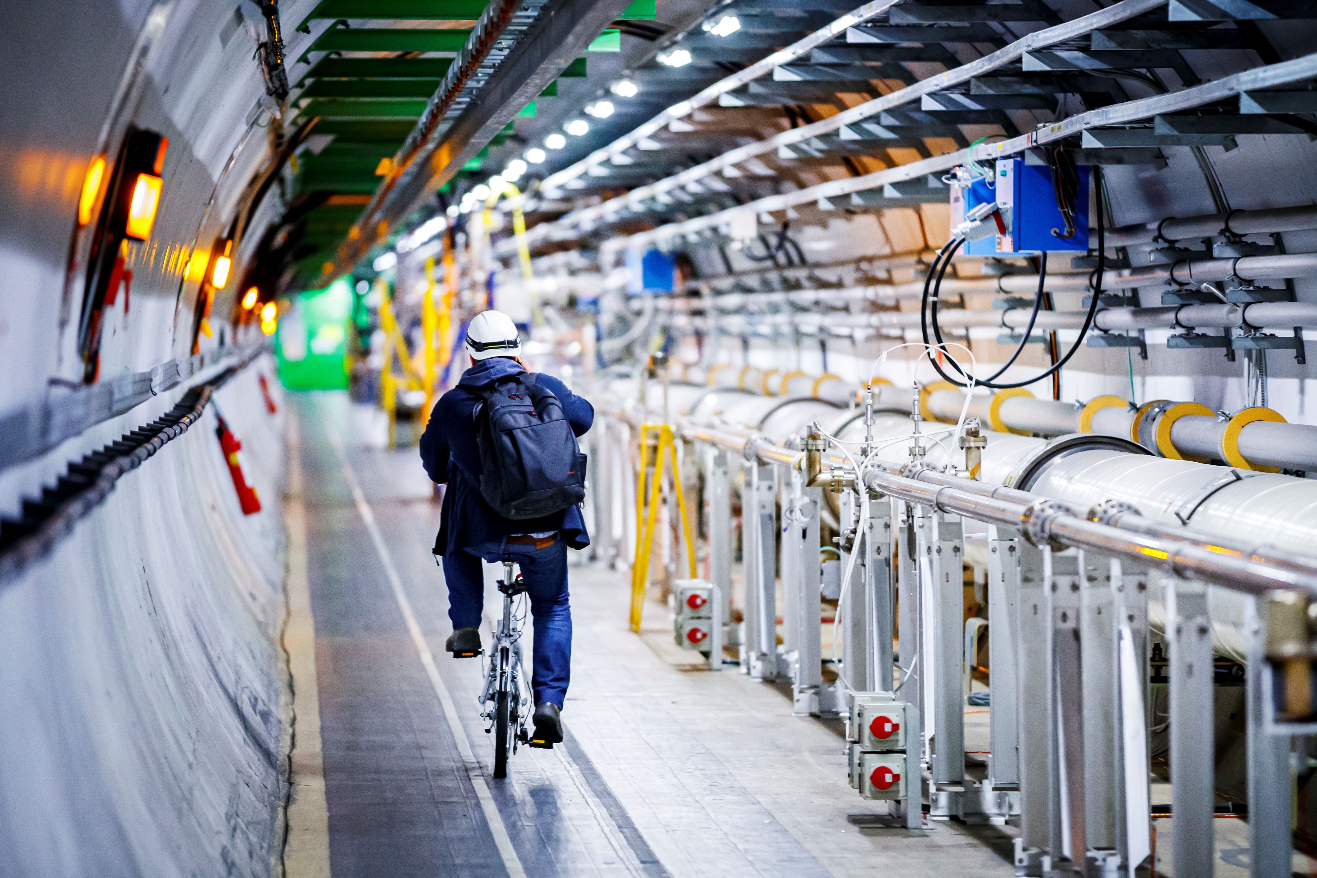 A man rides his bicycle along the underground Large Hadron Collider during its hiatus in 2020. The particle accelerator began smashing particles against on Tuesday 5 July