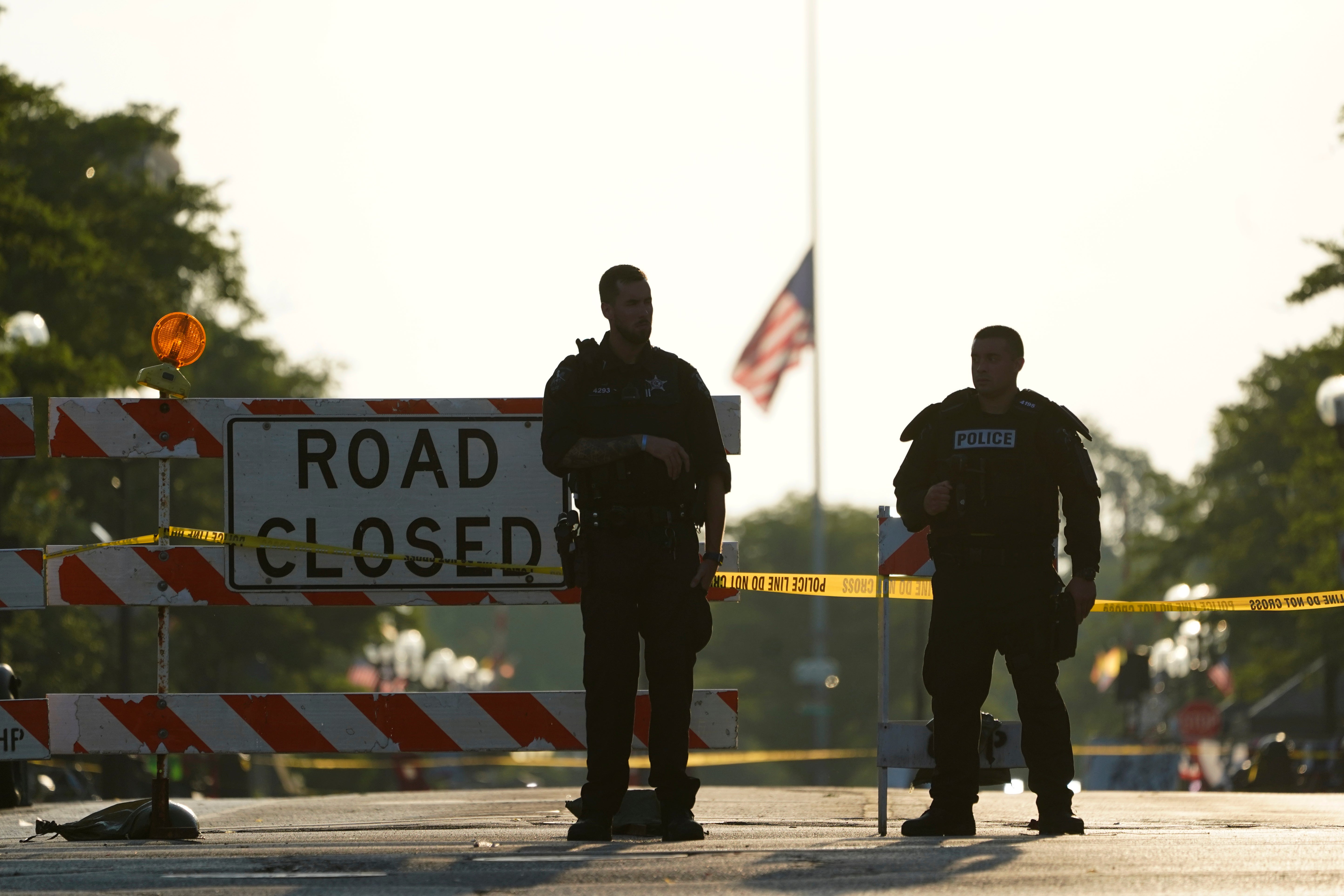 Two police officers stand their post, the day after a deadly mass shooting, on the Westside of the Highland Park