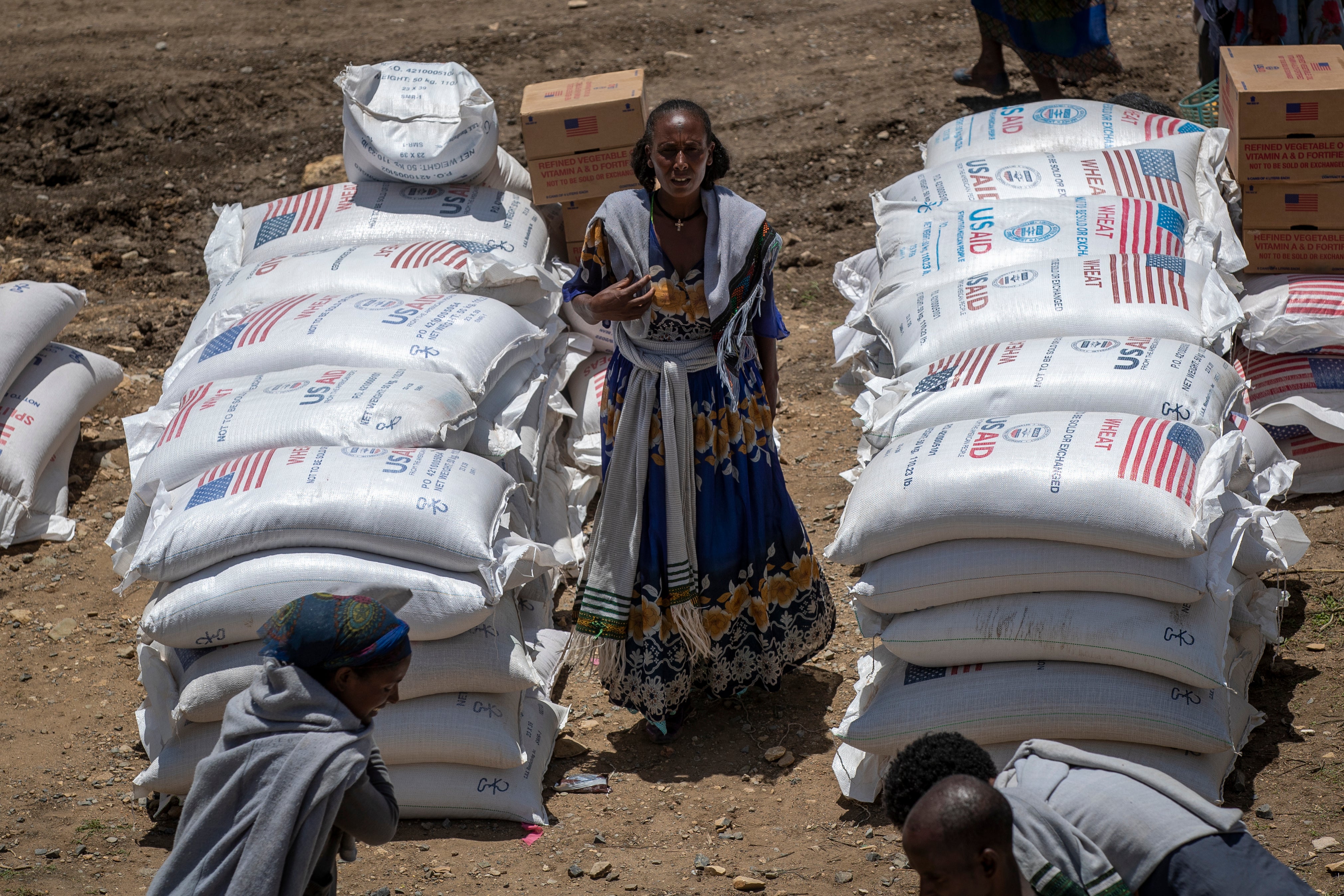 An Ethiopian woman stands by sacks of wheat to be distributed by the Relief Society of Tigray in the town of Agula