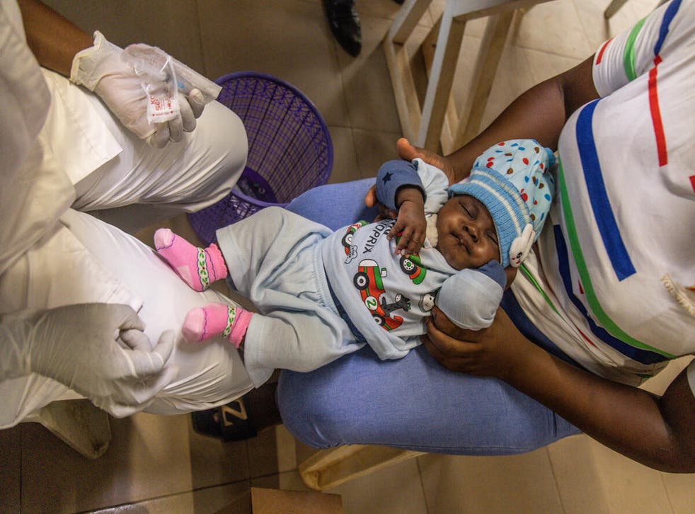 <p>Olatunji administers a vaccine to a child</p>