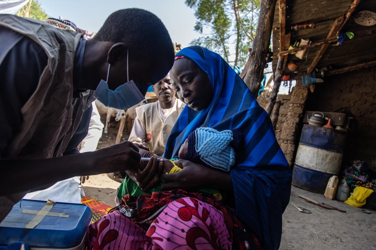 Healthworker Nura Ibrahim administers a vaccine to 22-day-old Rukayya outside his home in Jigawa state