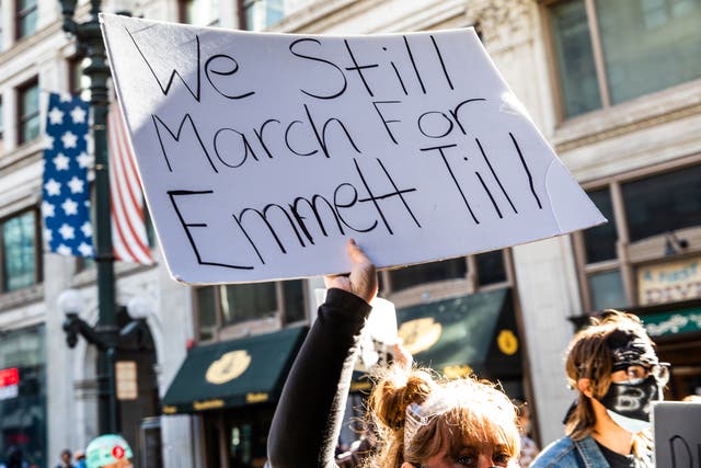 <p>A woman holds a sign in honor of Emmett Till during a protest on June 13, 2020 in Chicago, Illinois</p>