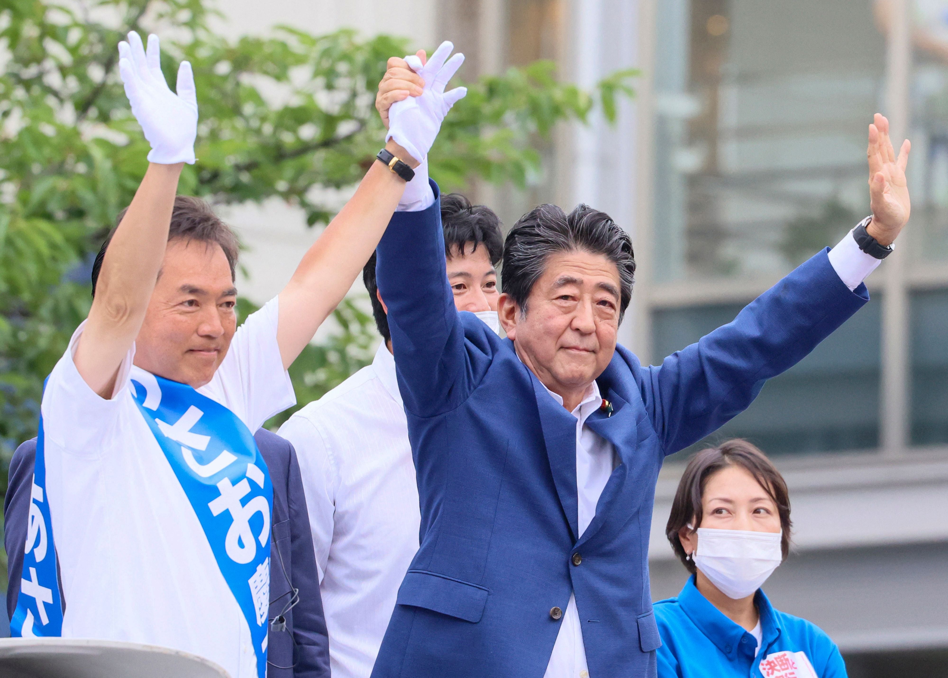 Former Japanese prime minister Shinzo Abe cheering at an event on Wednesday with Liberal Democratic Party candidate Keiichiro Asao