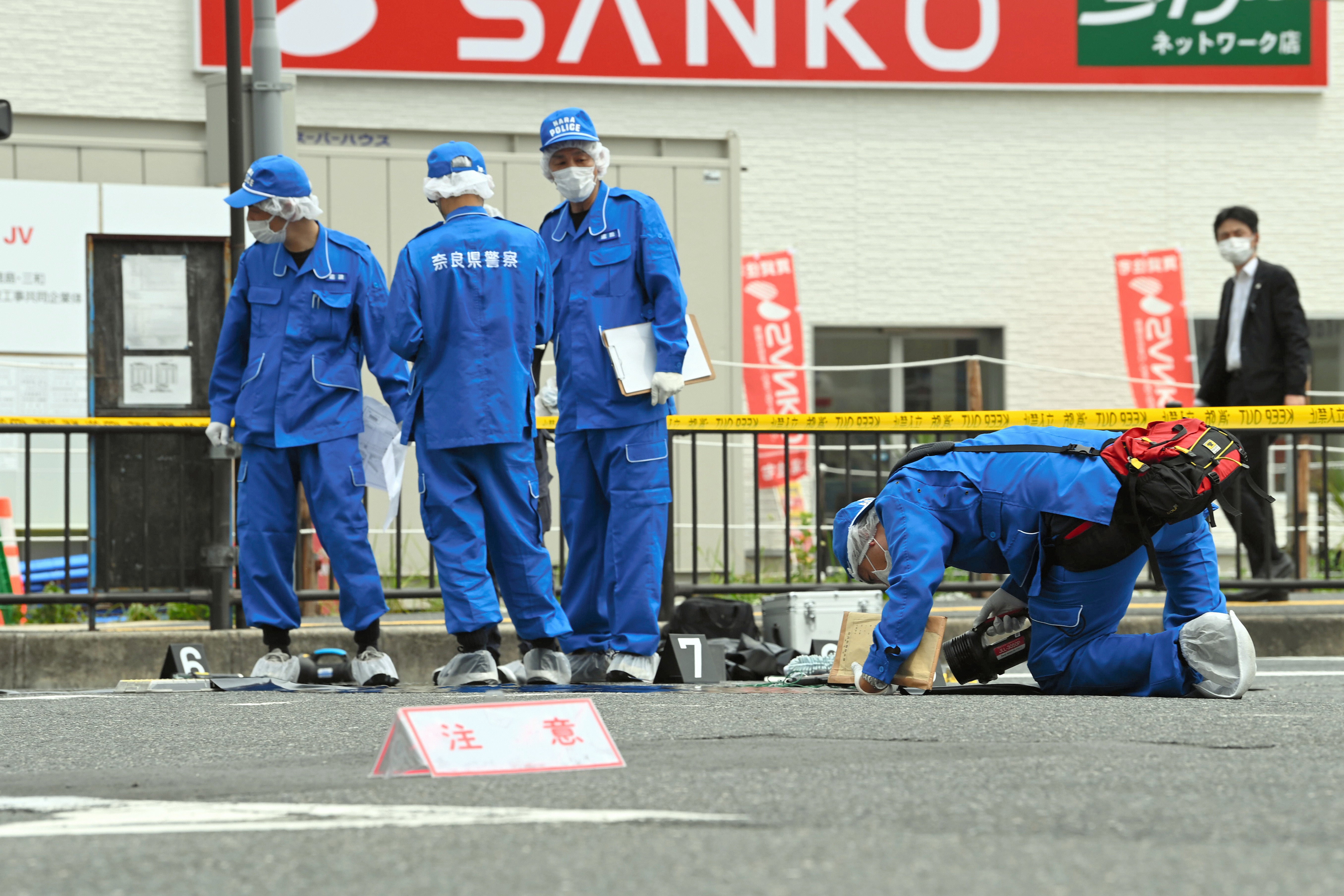 Officers investigate the site where former PM Shinzo Abe was shot while making a speech in front of Yamatosaidaiji Station on 8 July in Nara, Japan