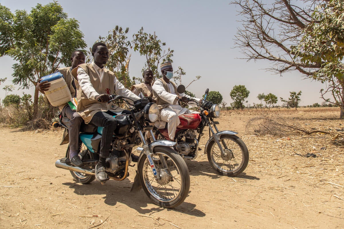 A mobile vaccination team travelling by motorbike to a remote community