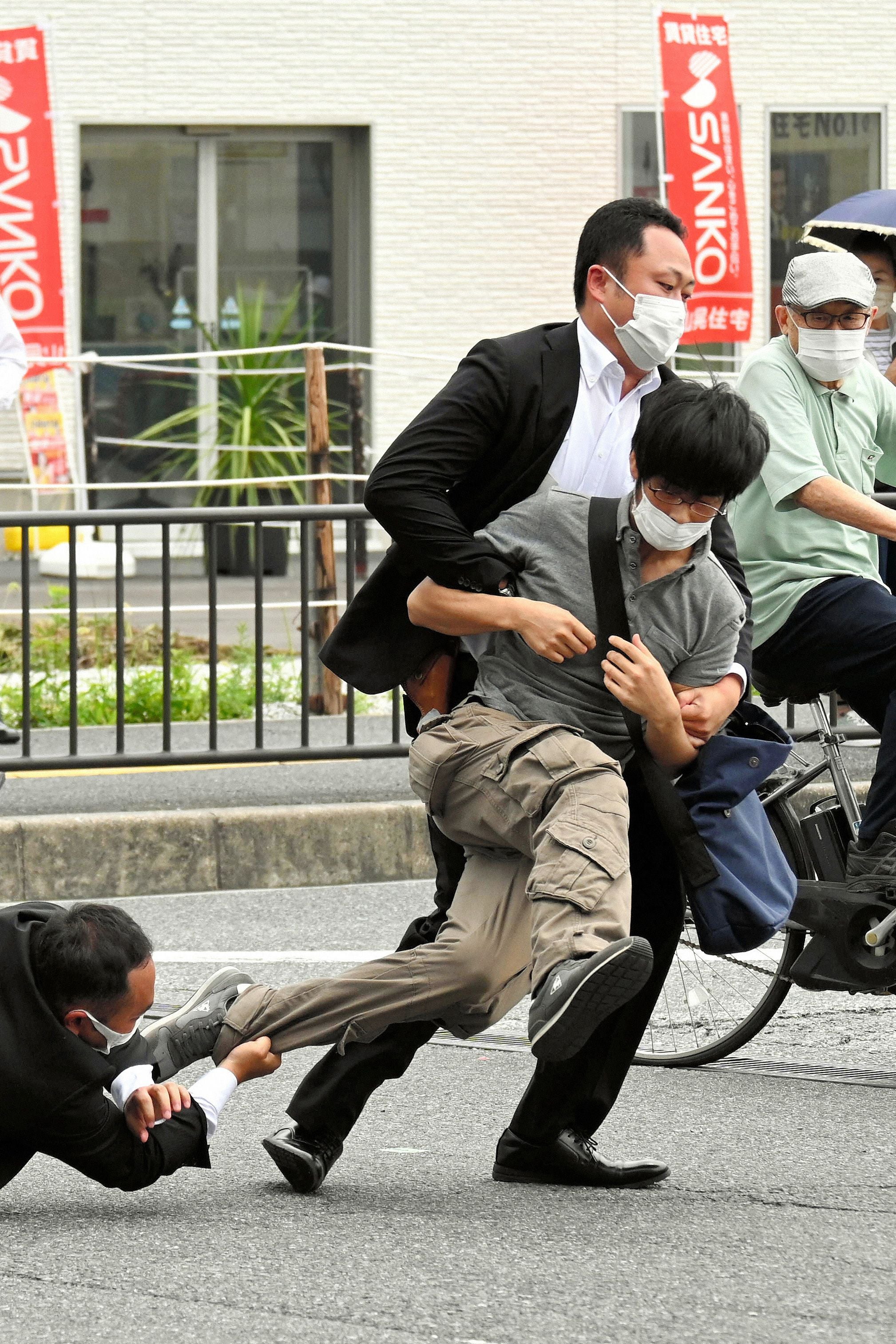 This image received from the Asahi Shimbun newspaper shows a man (centre) suspected of shooting former Japanese prime minister Shinzo Abe being tackled to the ground by police