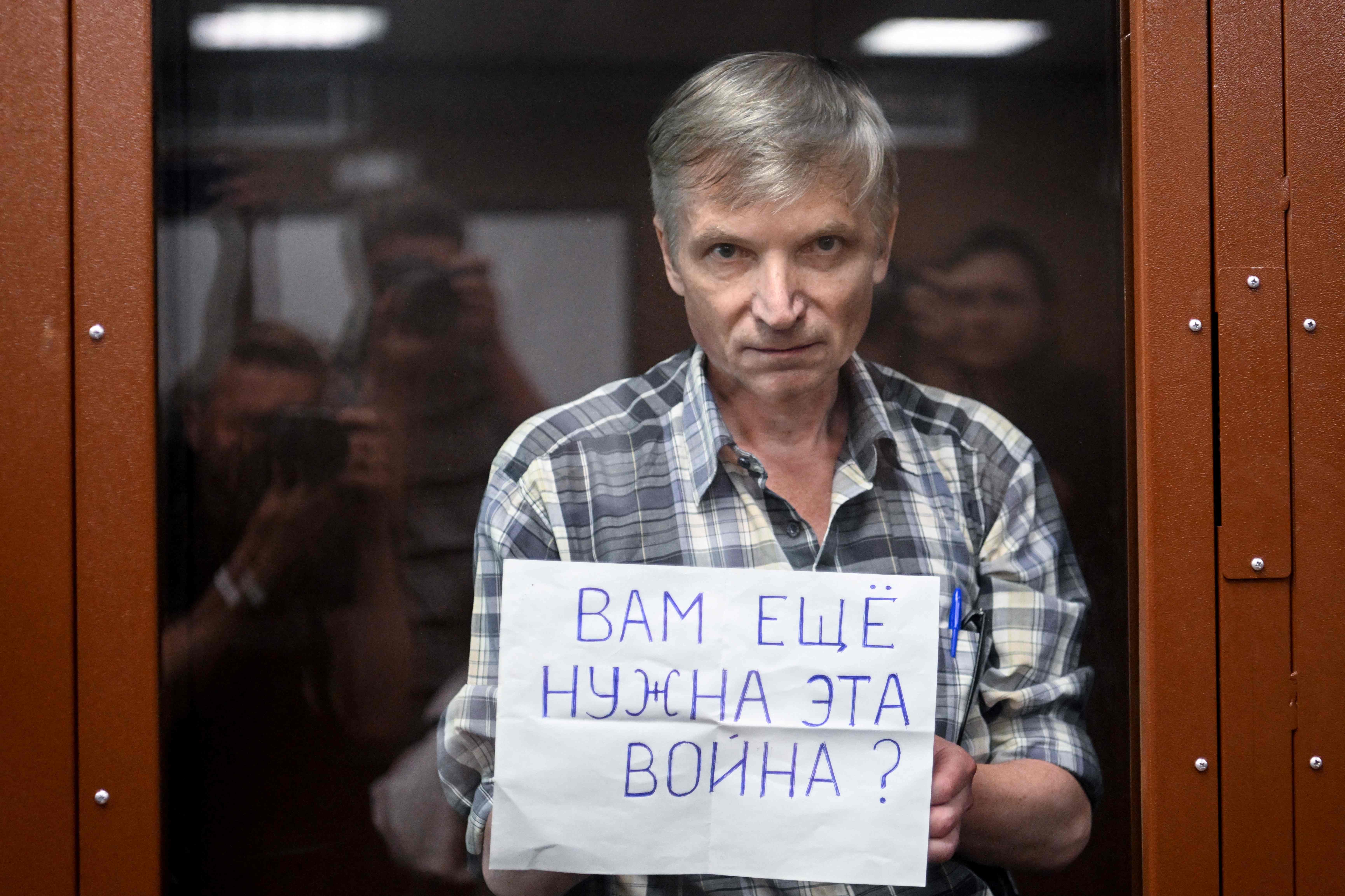 Alexei Gorinov stands with a poster reading, ‘Do you still need this war?’