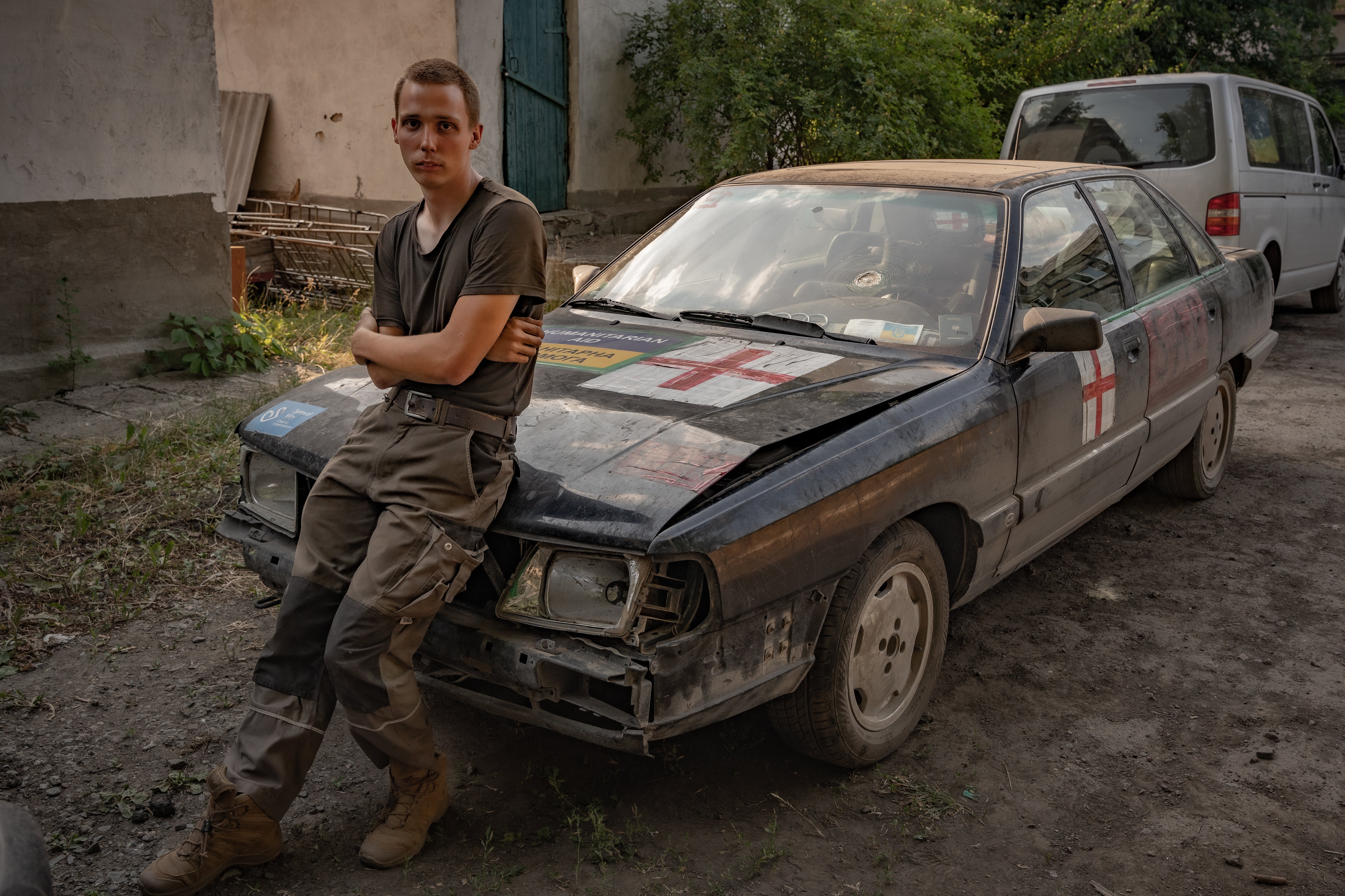 Andrei, a German volunteer, sits on the shelled car he has used to rescue over 250 civilians from the hardest hit areas