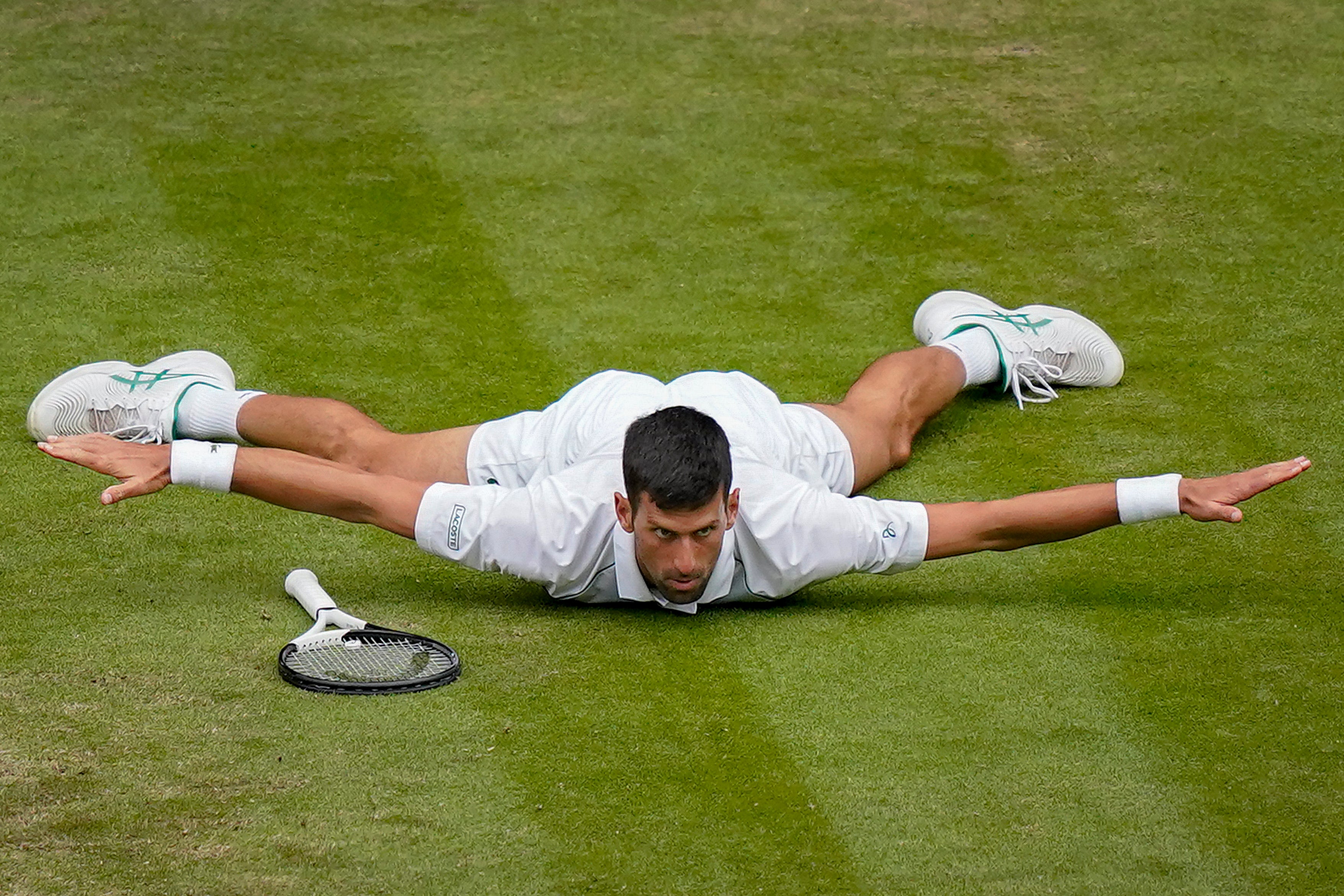 Novak Djokovic lies front on his chest after a terrific winner against Jannik Sinner at Wimbledon 2022