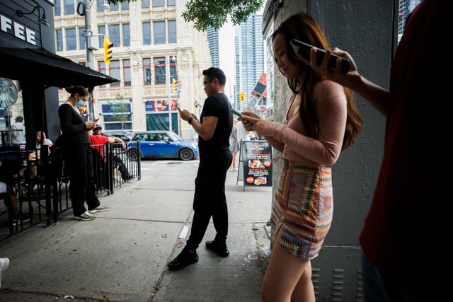 <p>People use electronics outside a coffee shop in Toronto amid a nationwide Rogers outage, affecting many of the telecommunication company's services, Friday, 8 July 2022 </p>