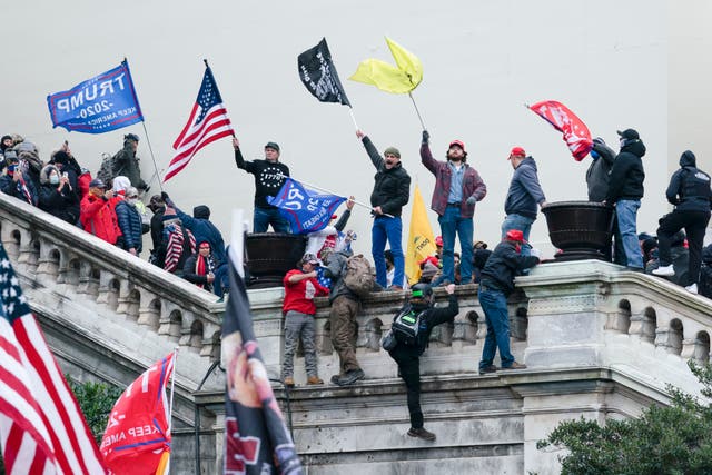 <p>Rioters wave flags during the insurrection on Capitol Hill on 6 January 2021 </p>