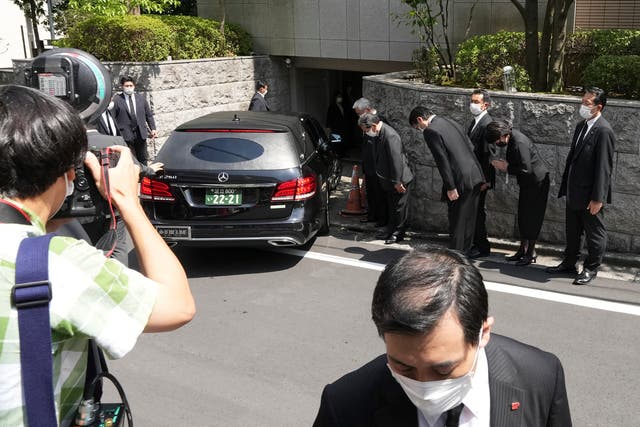 <p>People pay their respects as a hearse believed to be carrying the body of former prime minister Shinzo Abe arrives at his home on Saturday</p>