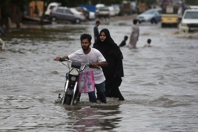 Un hombre empuja su motocicleta por una calle inundada después de una lluvia monzónica en Karachi.