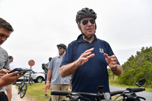 <p>President Joe Biden stops to talk to reporters during a bike ride in Rehobeth Beach, Delaware, on 10 July</p>