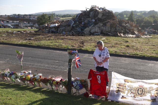 Lucinda McFall laying flowers near the scene after a man died after falling from a bonfire on the Antiville estate in Larne, Co Antrim last night. Police and ambulance personnel attended the scene after the fatal incident, which happened just after 9.30pm. Picture date: Sunday July 10, 2022.