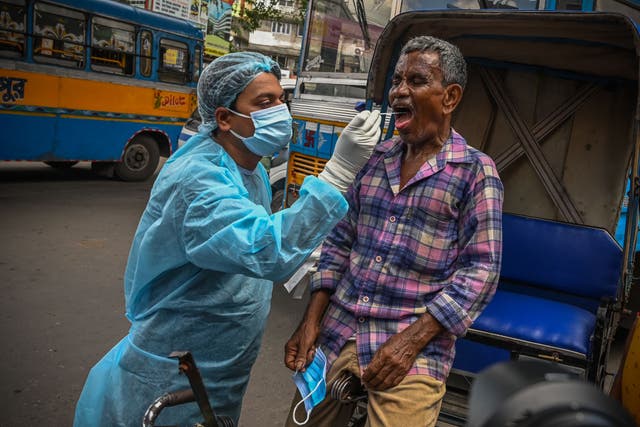 <p>Health workers collect swab samples from commuters for Covid-19 coronavirus screening after a surge in India on 4 July</p>
