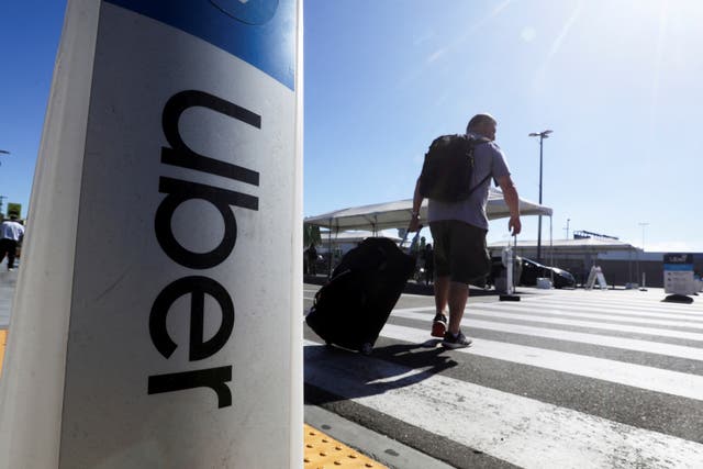 <p>A passenger walks near Uber signage after arriving at Los Angeles International Airport in Los Angeles</p>