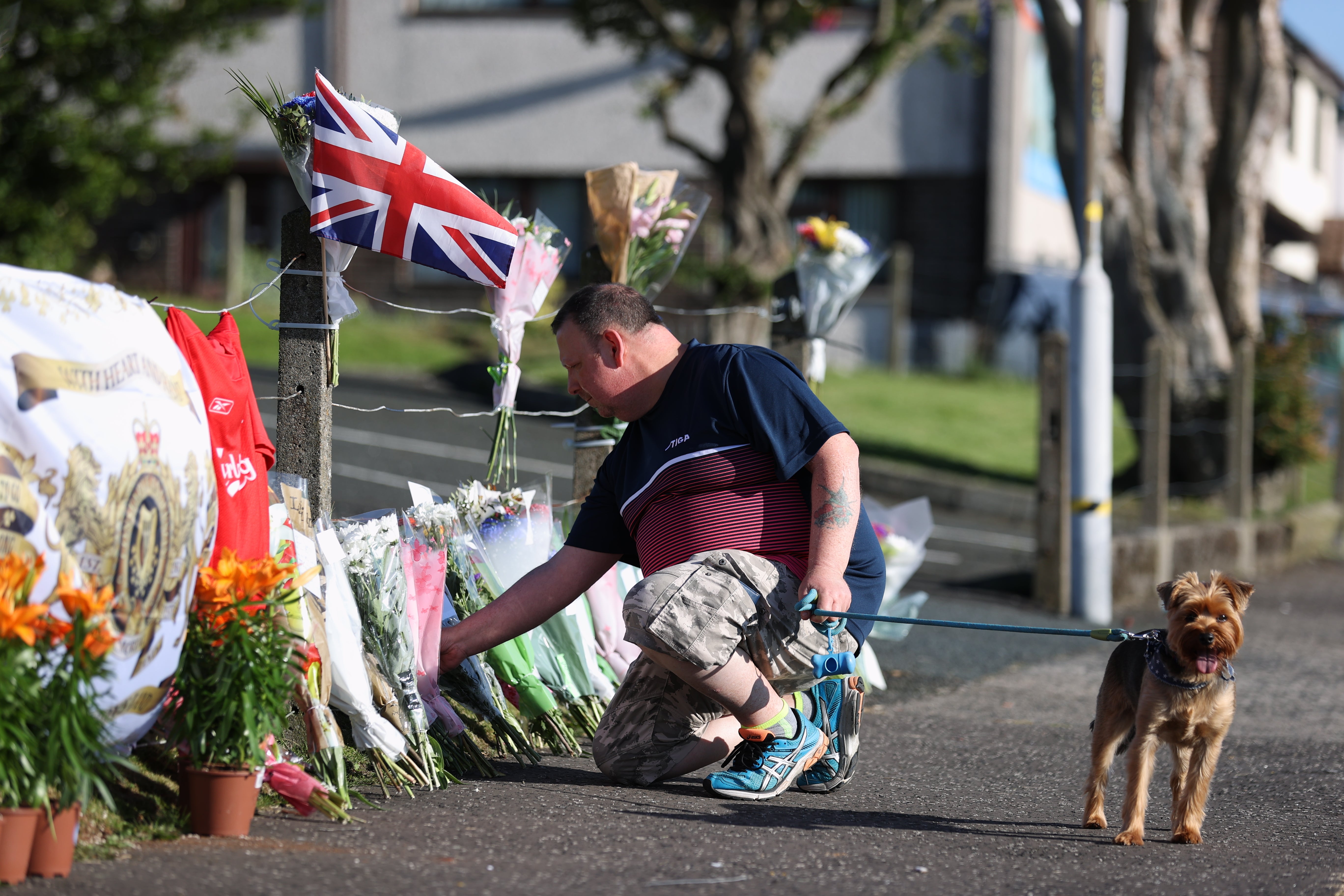 A man lays flowers near the scene after a man died after falling from a bonfire on the Antiville estate in Larne, Co Antrim on Saturday night. Police and ambulance personnel attended the scene after the fatal incident, which happened just after 9.30pm. Picture date: Sunday July 10, 2022 (Liam McBurney/PA)